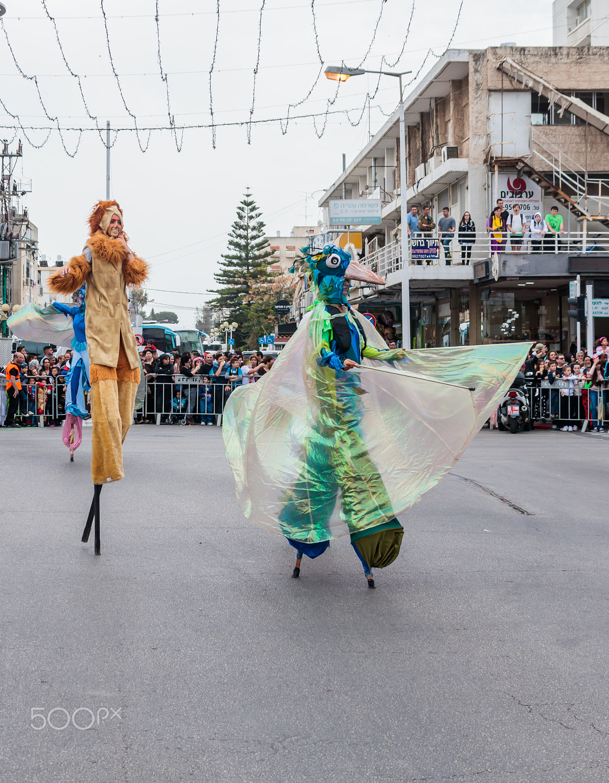 Canon EF 75-300mm F4.0-5.6 IS USM sample photo. Participants at carnival on stilts are walking along the street photography