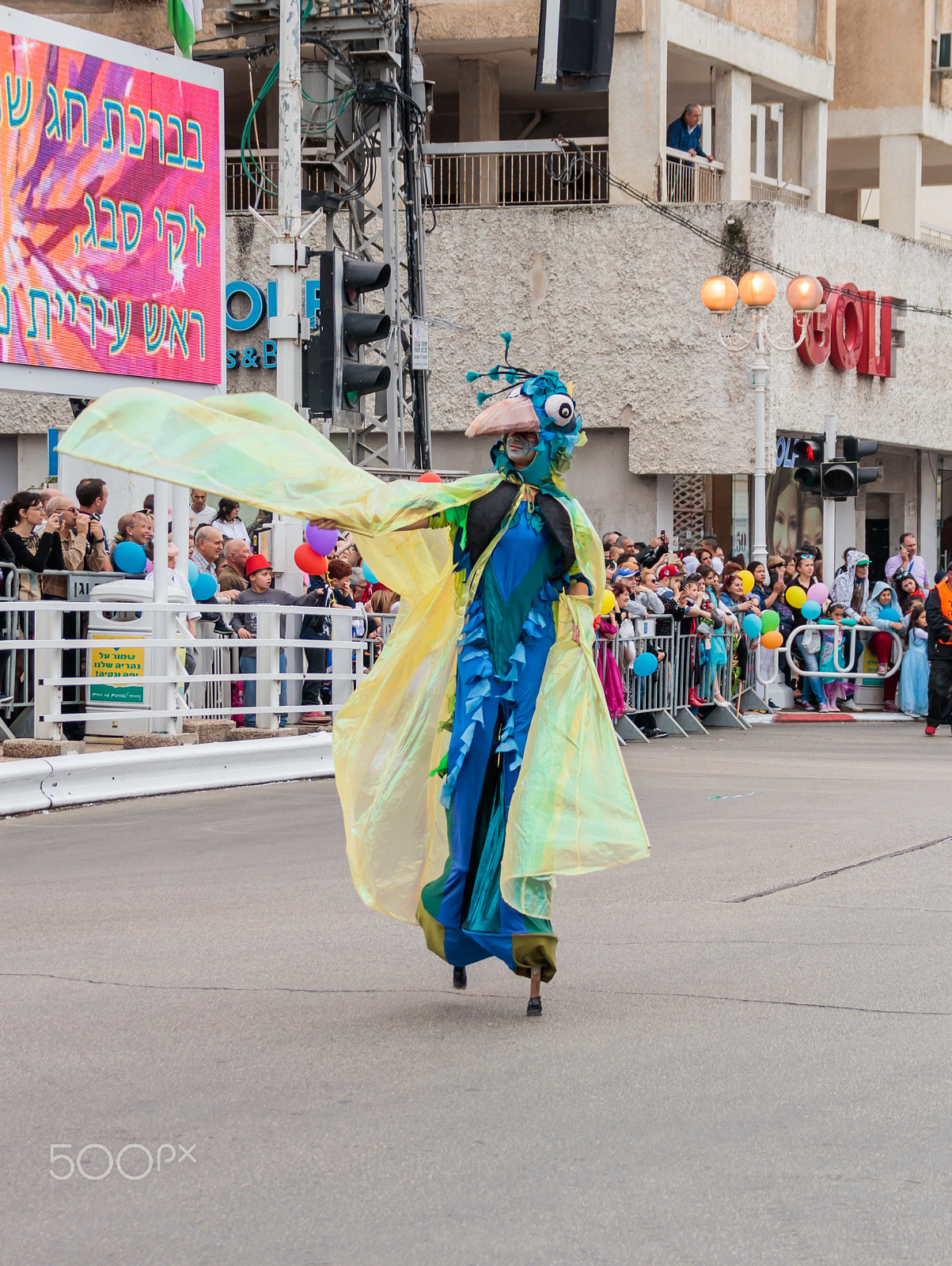 Canon EF 75-300mm F4.0-5.6 IS USM sample photo. Participants at carnival on stilts are walking along the street photography