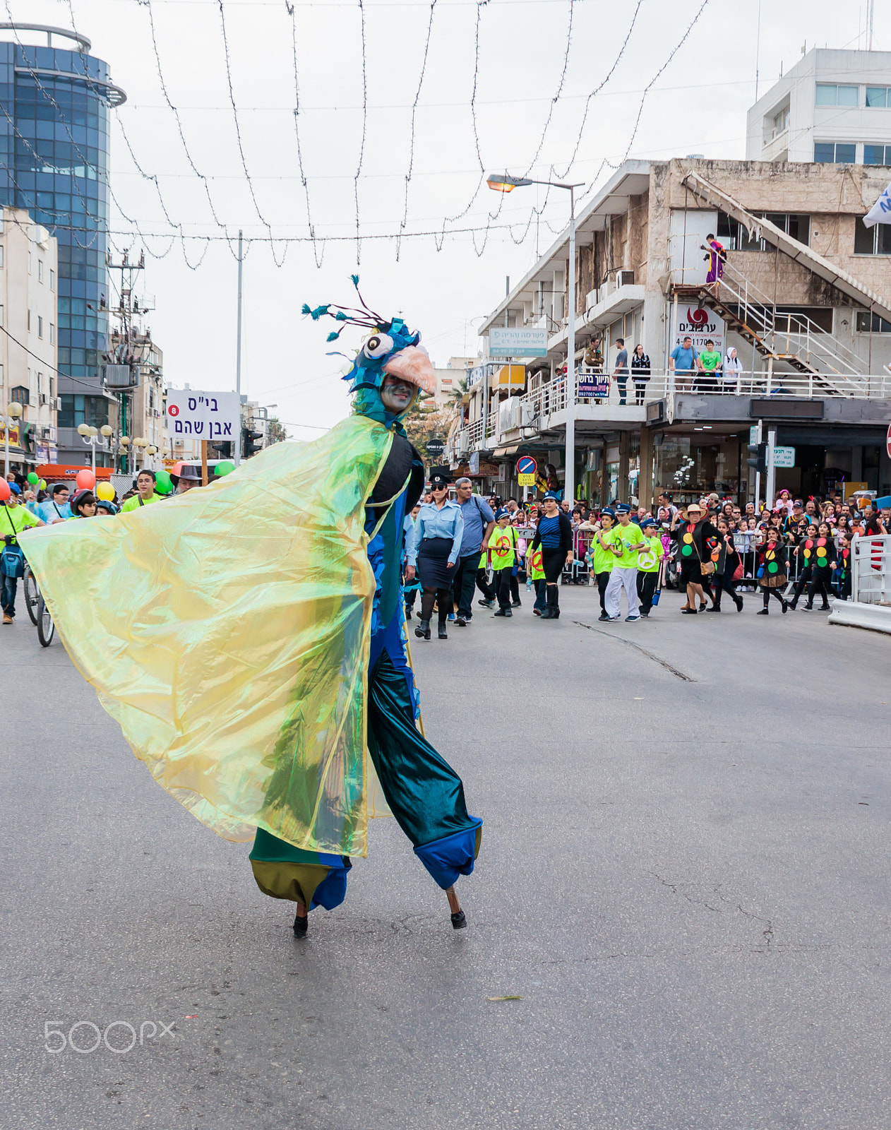 Canon EF 75-300mm F4.0-5.6 IS USM sample photo. Participants at carnival on stilts are walking along the street photography