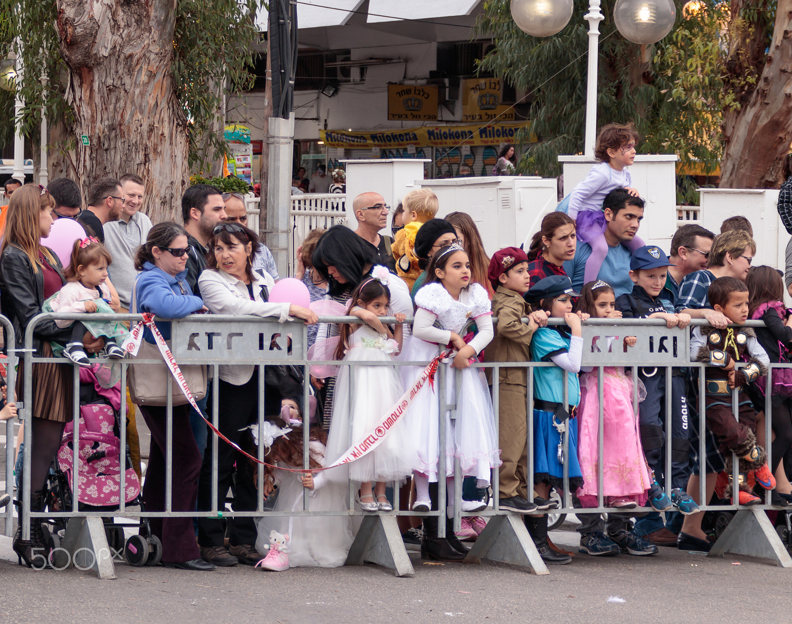 Canon EF 75-300mm F4.0-5.6 IS USM sample photo. Viewers from behind dividing fence look at the carnival parade photography