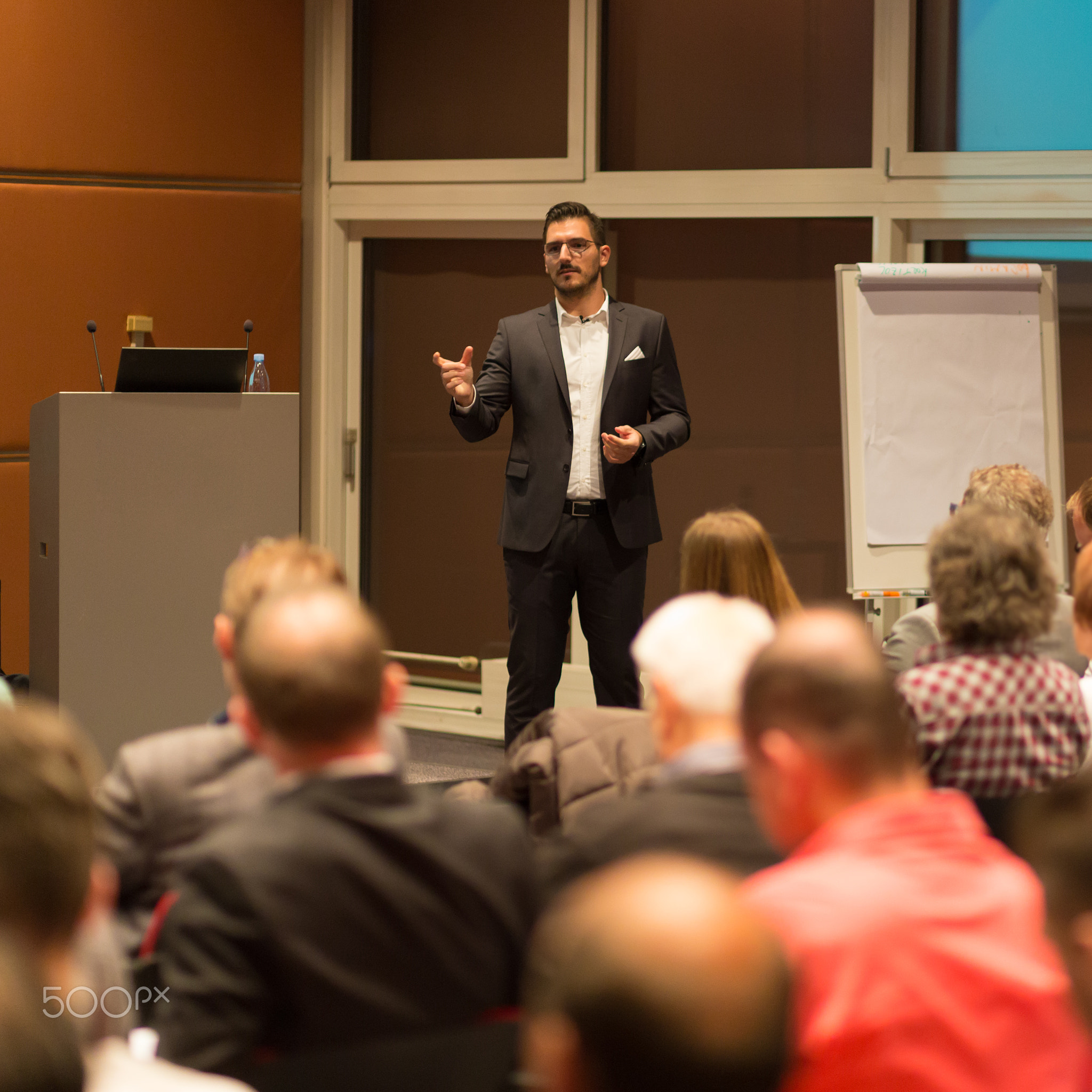 Business speaker giving a talk in conference hall.