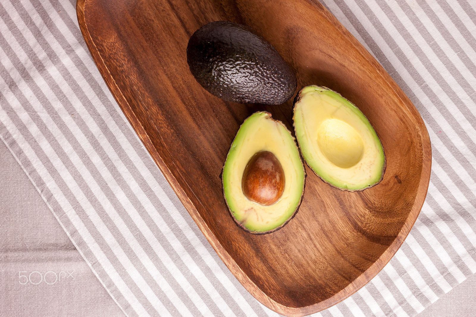 Canon EOS 500D (EOS Rebel T1i / EOS Kiss X3) + Canon EF 40mm F2.8 STM sample photo. Avocado on wooden plate photography