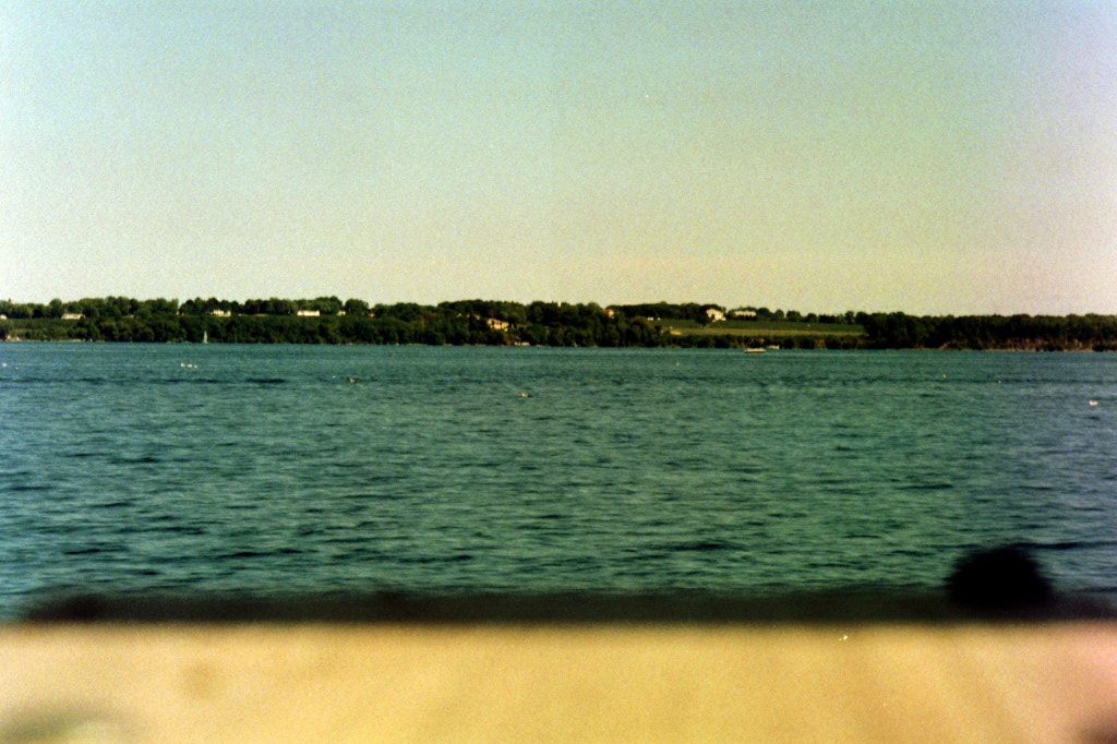 Low-fidelity view of lakewater, with trees and grass far in the background.
