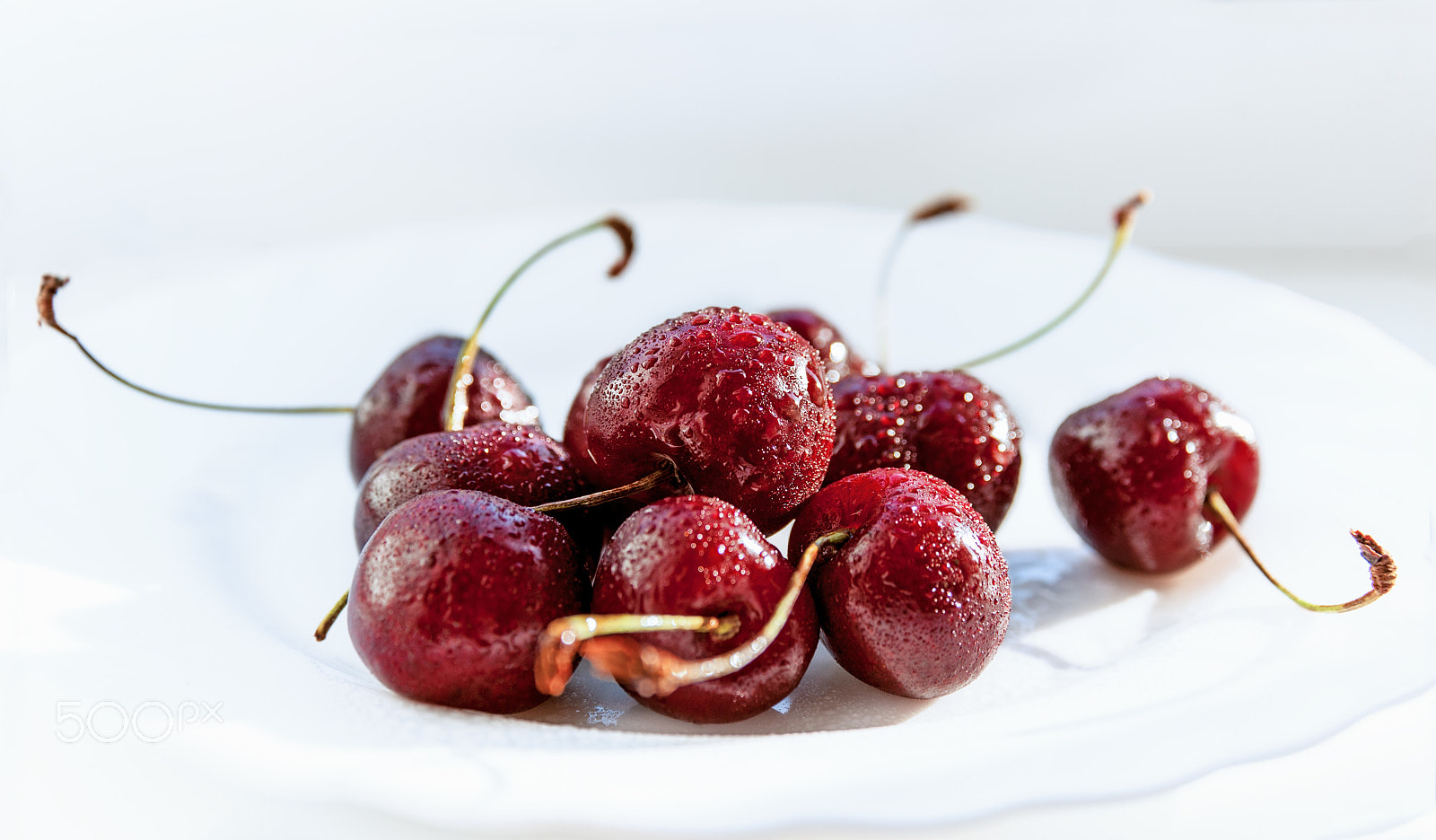 Nikon D700 sample photo. Wet cherries lying on a white plate on a light background photography