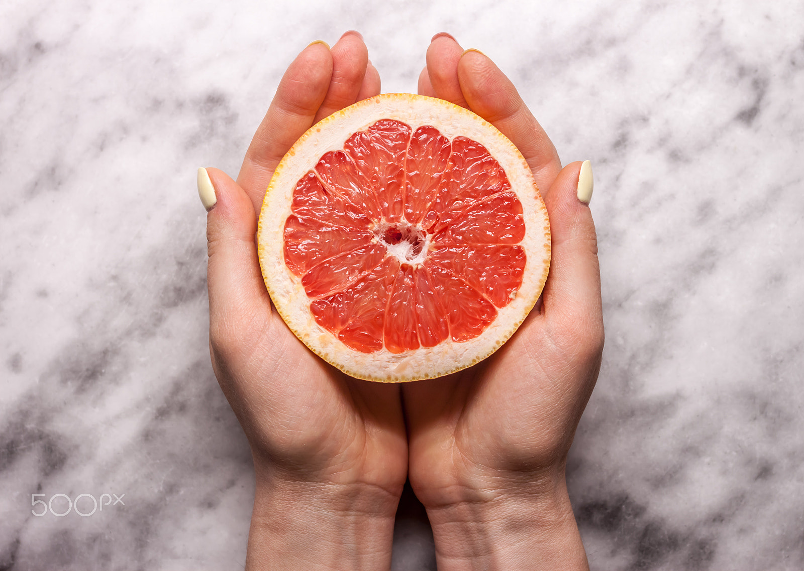 Canon EOS 500D (EOS Rebel T1i / EOS Kiss X3) + Canon EF 40mm F2.8 STM sample photo. Female hands keeping cut grapefruit photography