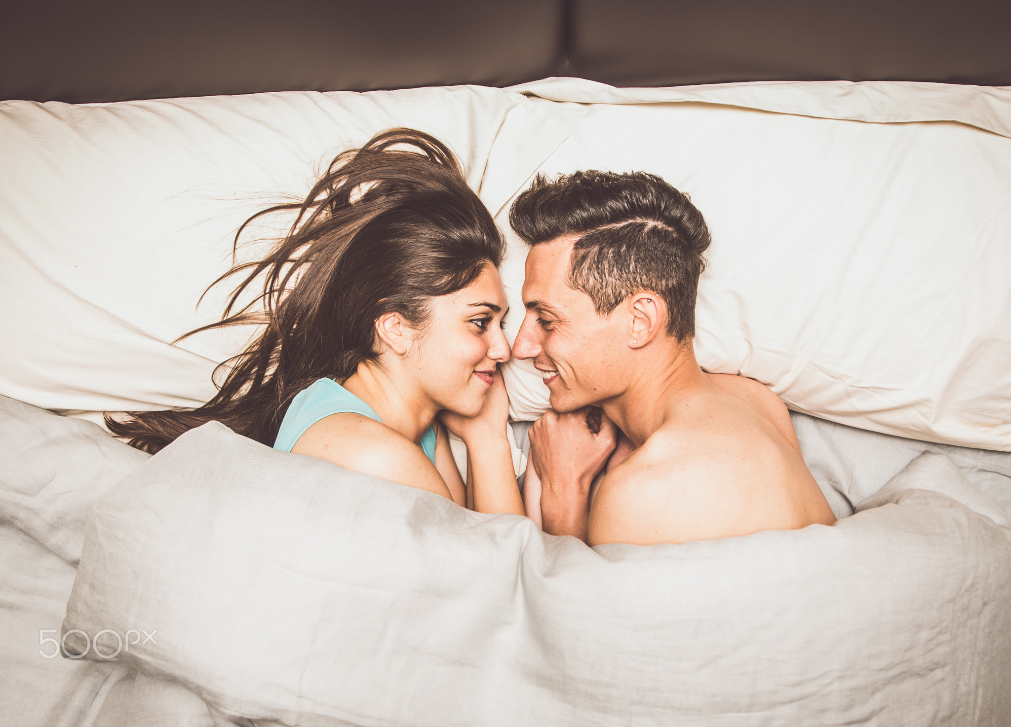 Couple in bed, sharing looks and love emotions