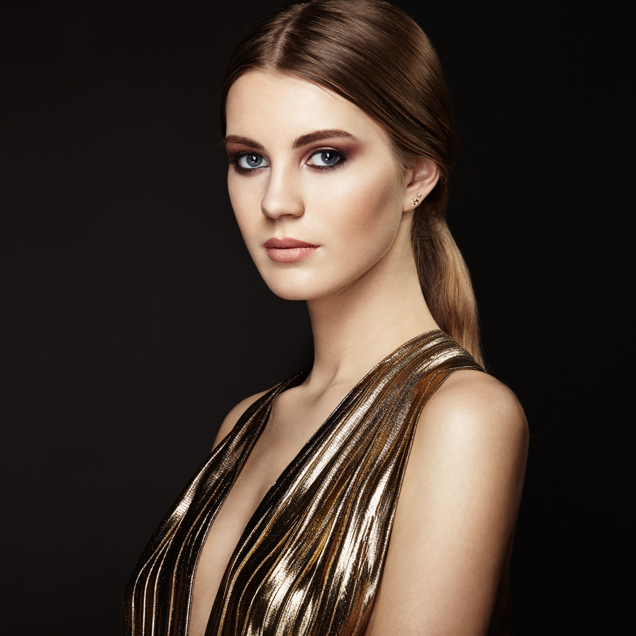 Fashion portrait of young beautiful woman in gold dress