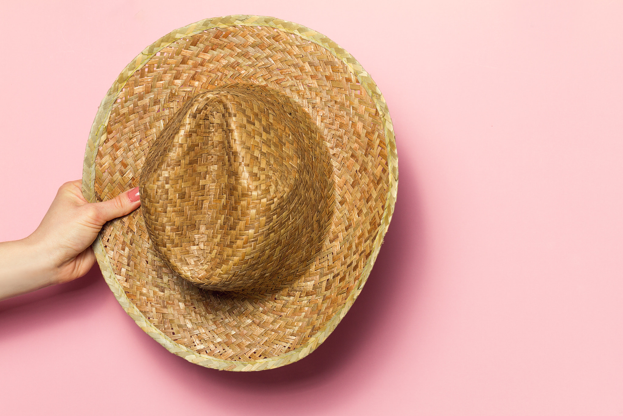 Canon EOS 7D + Canon EF 24-70mm F4L IS USM sample photo. Hand of young woman holding summer straw hat on pink background. photography