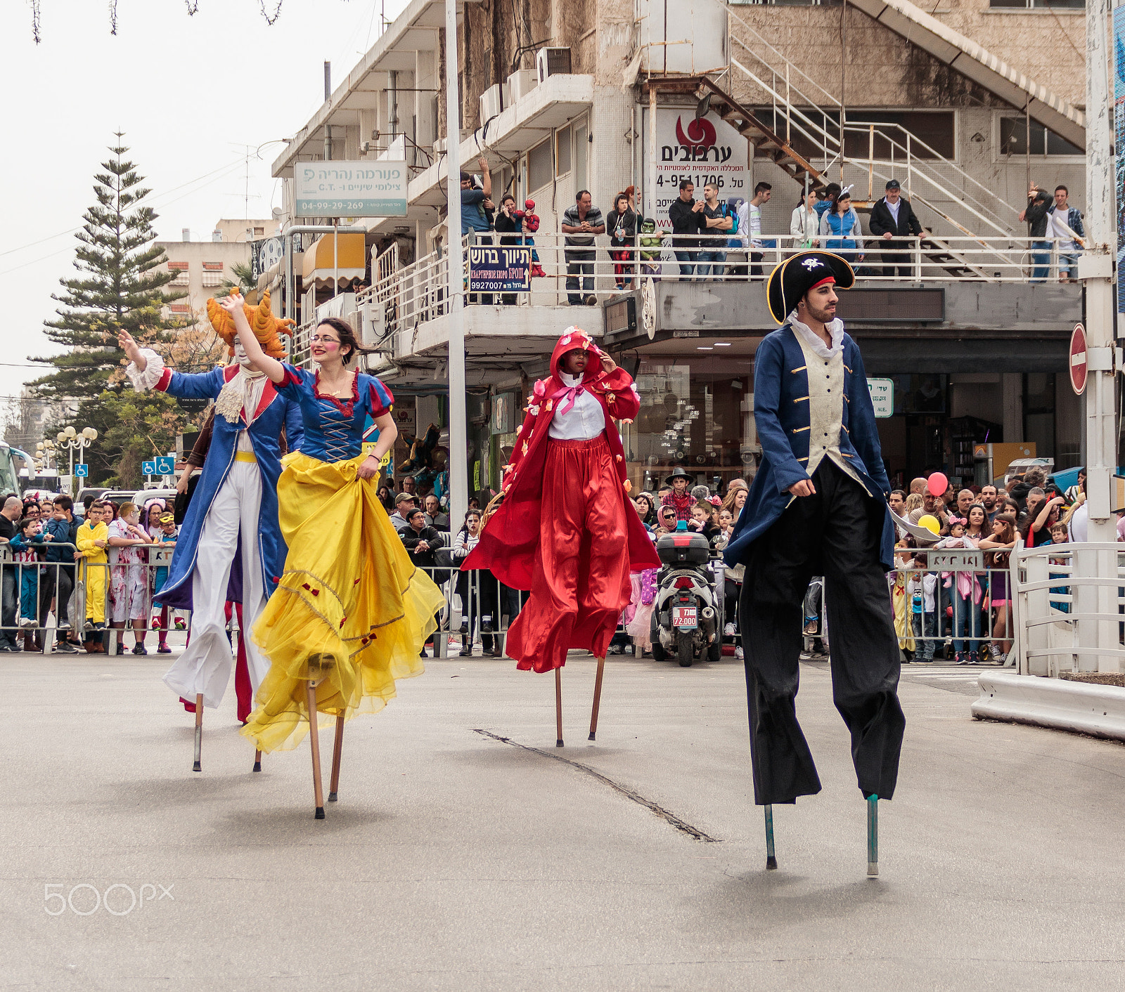 Canon EF 75-300mm F4.0-5.6 IS USM sample photo. Participants at carnival on stilts are walking along the street photography
