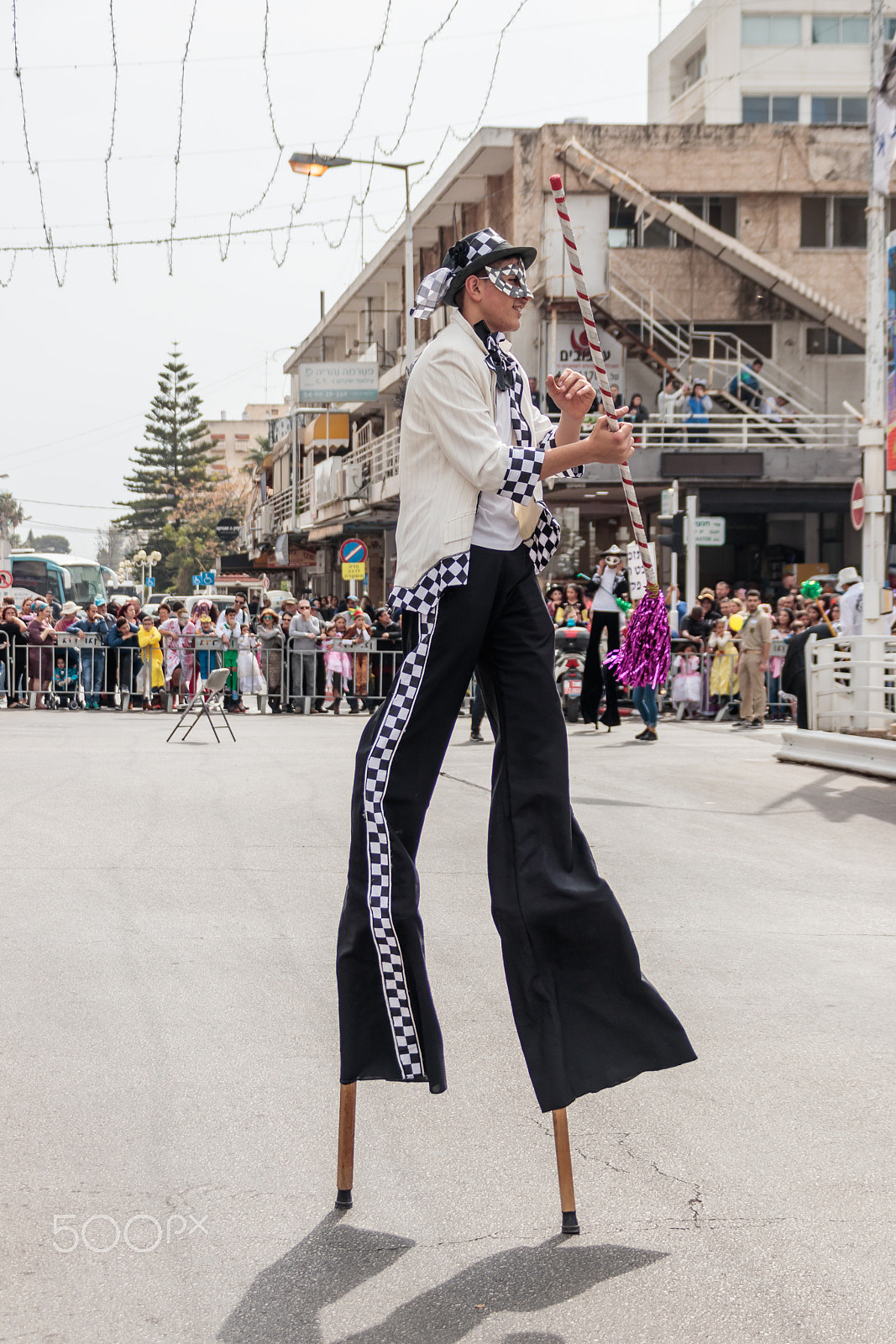 Canon EF 75-300mm F4.0-5.6 IS USM sample photo. Participants at carnival on stilts are walking along the street photography