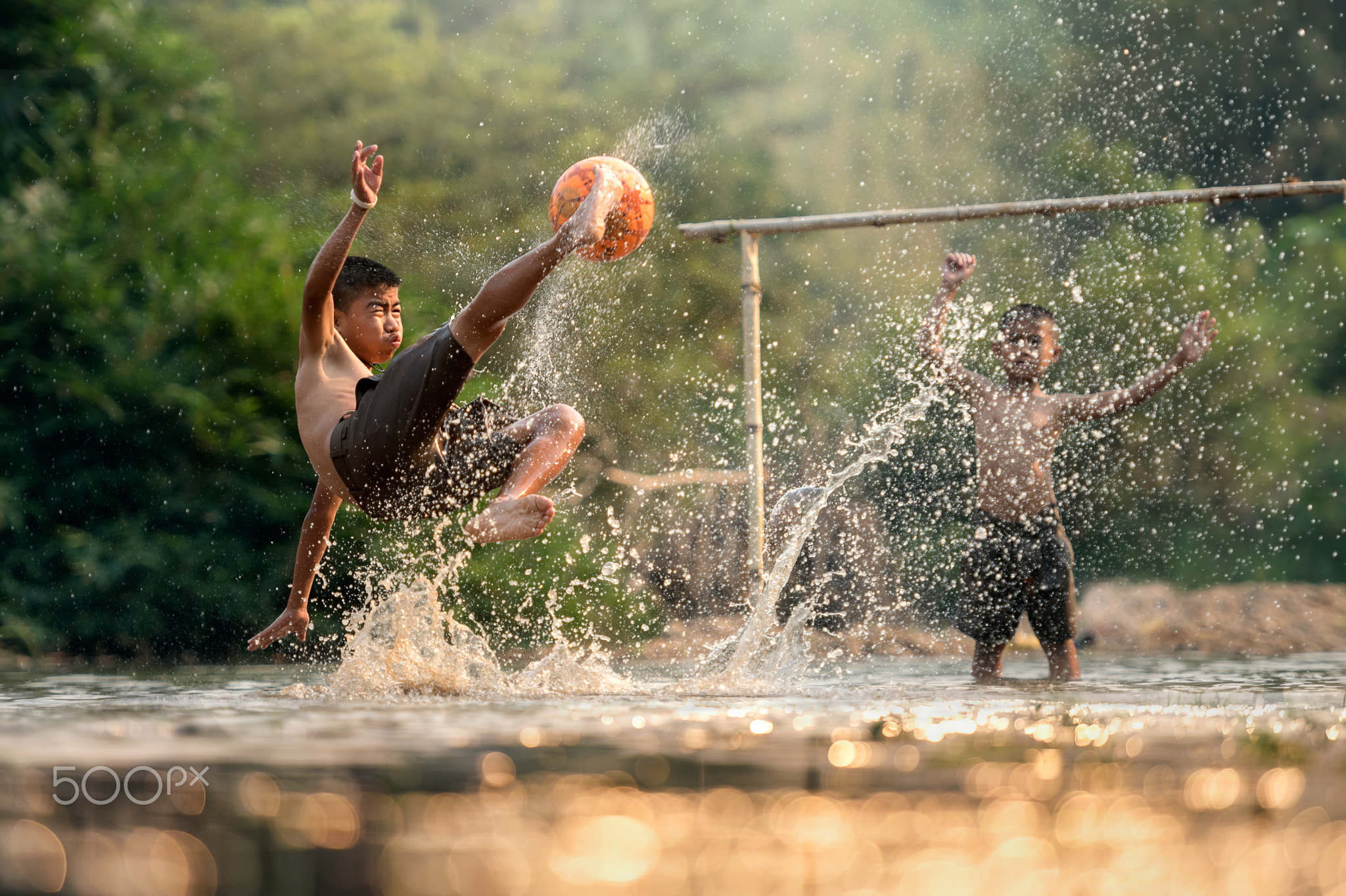 Boy kicking football in the river