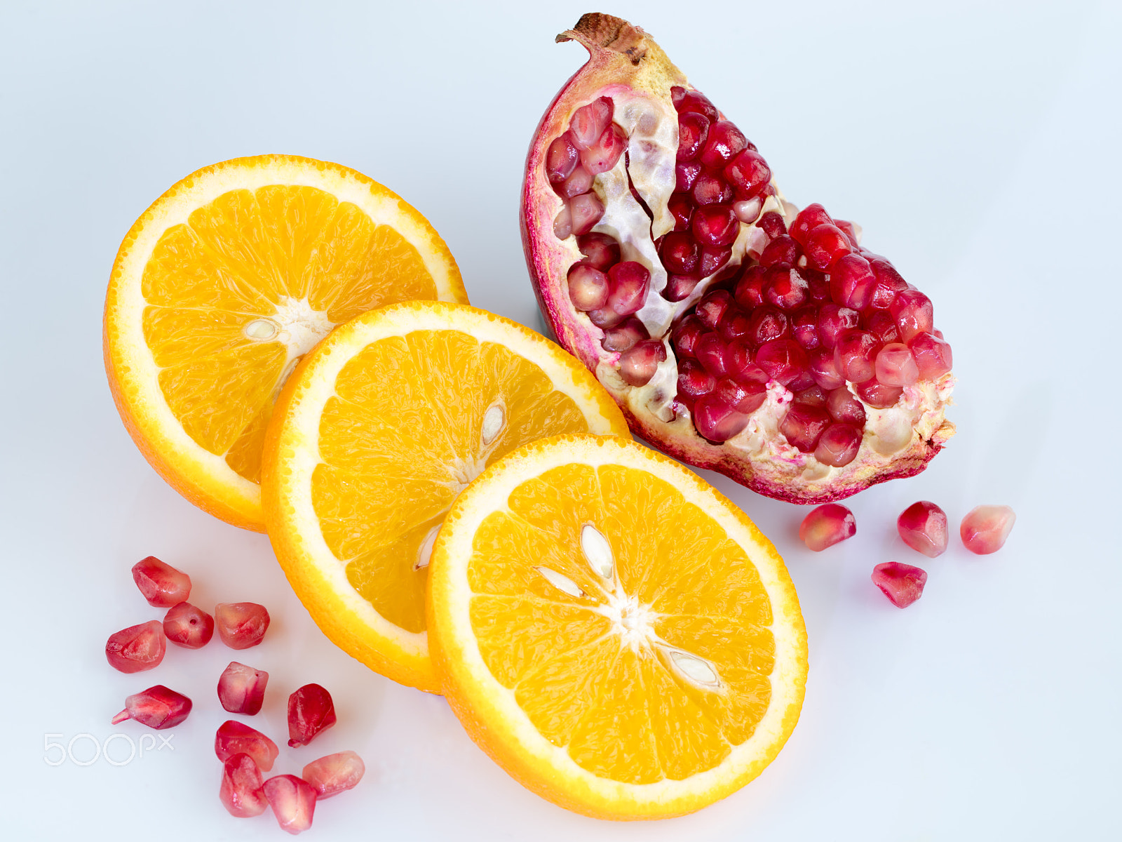 Canon EF 100mm F2.8L Macro IS USM sample photo. Sliced orange and pomegranate on a light blue background photography