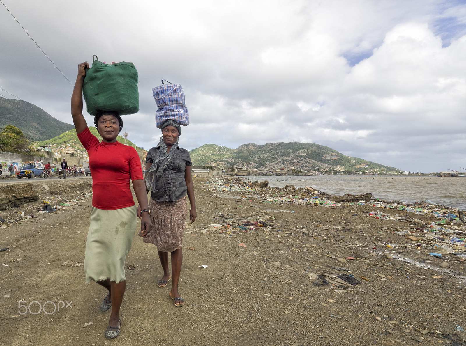 Olympus M.Zuiko Digital ED 7-14mm F2.8 PRO sample photo. Two women walk along the cape haitien beach, holding a pack over their heads. photography