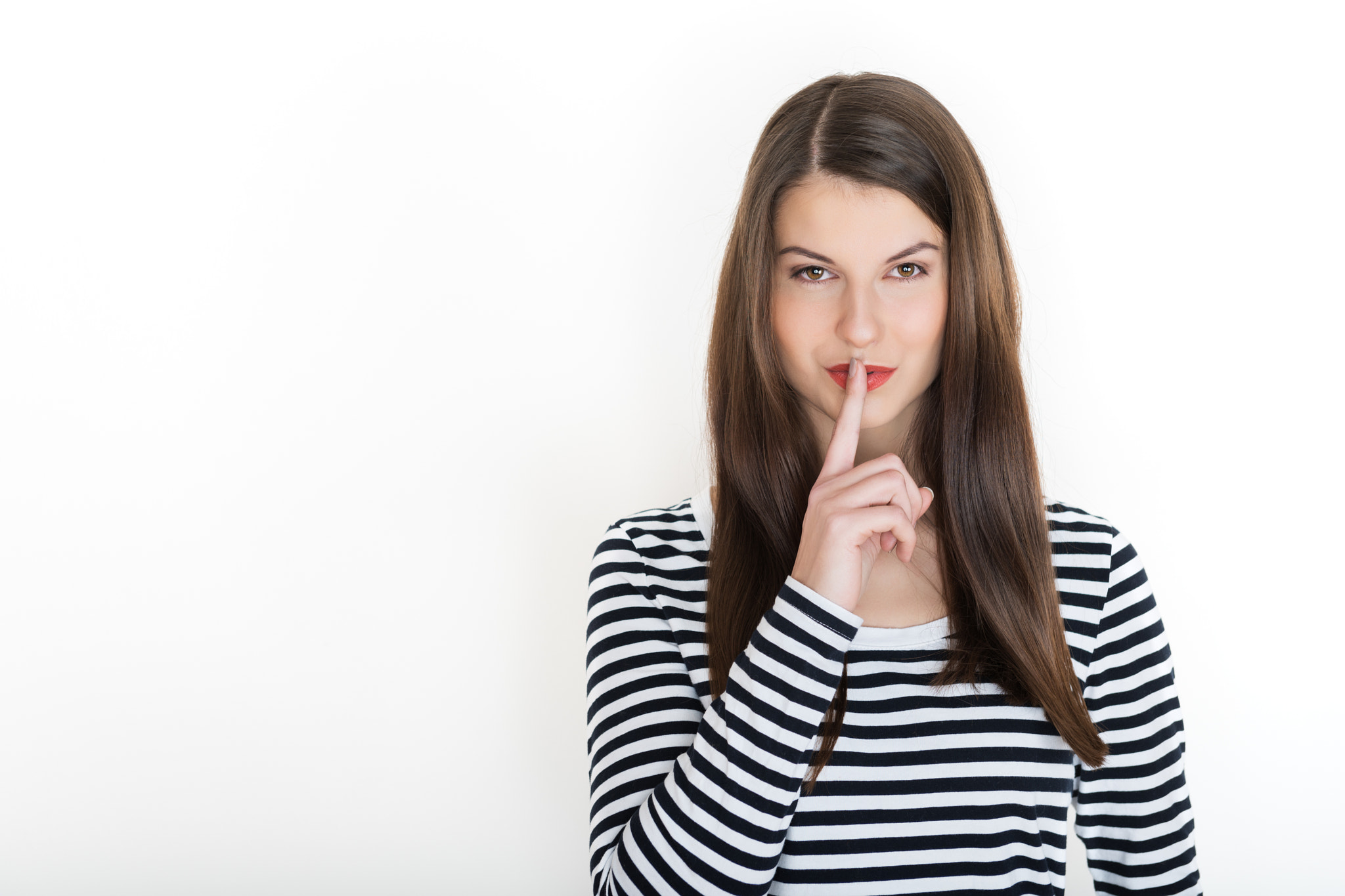 Woman holding her finger to her lips in a gesture for silence. Finger on lips - silent gesture.
