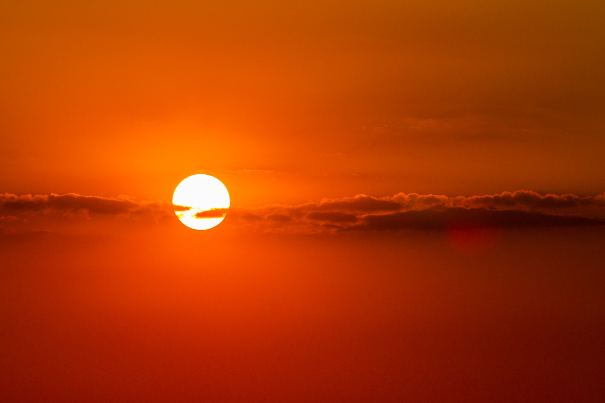 Canon EOS 7D + Canon EF 70-200mm F4L IS USM sample photo. Sun setting behind thin cloud line photography