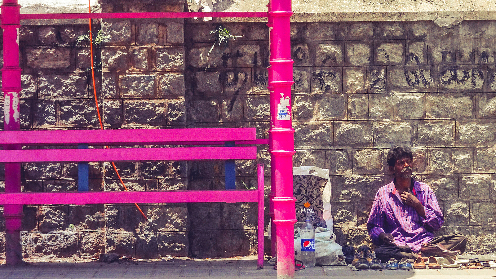 Sony Cyber-shot DSC-WX500 sample photo. A man sitting beside a colorful bus stand photography