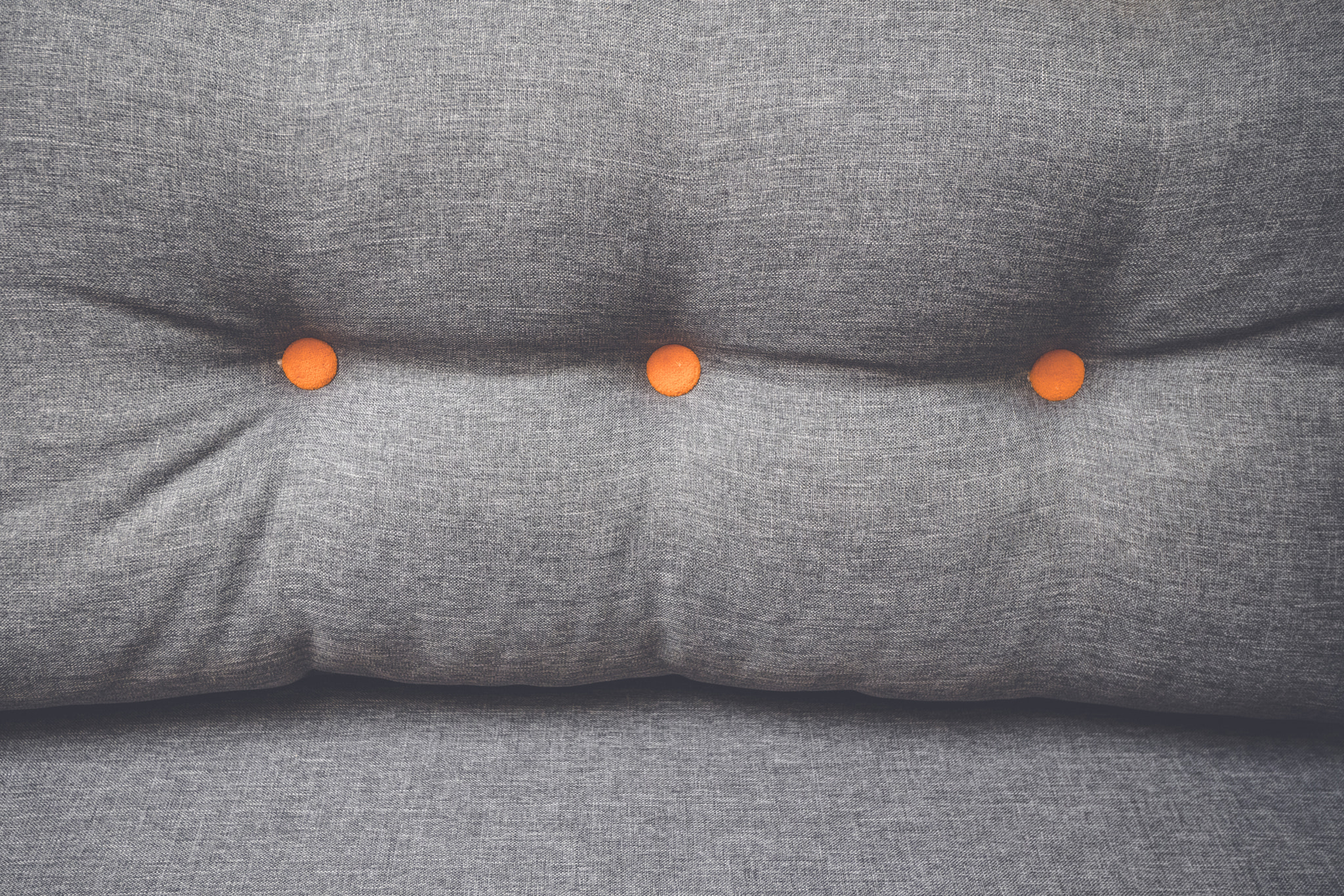 Sony a99 II sample photo. Pillow in grey color with orange buttons photography