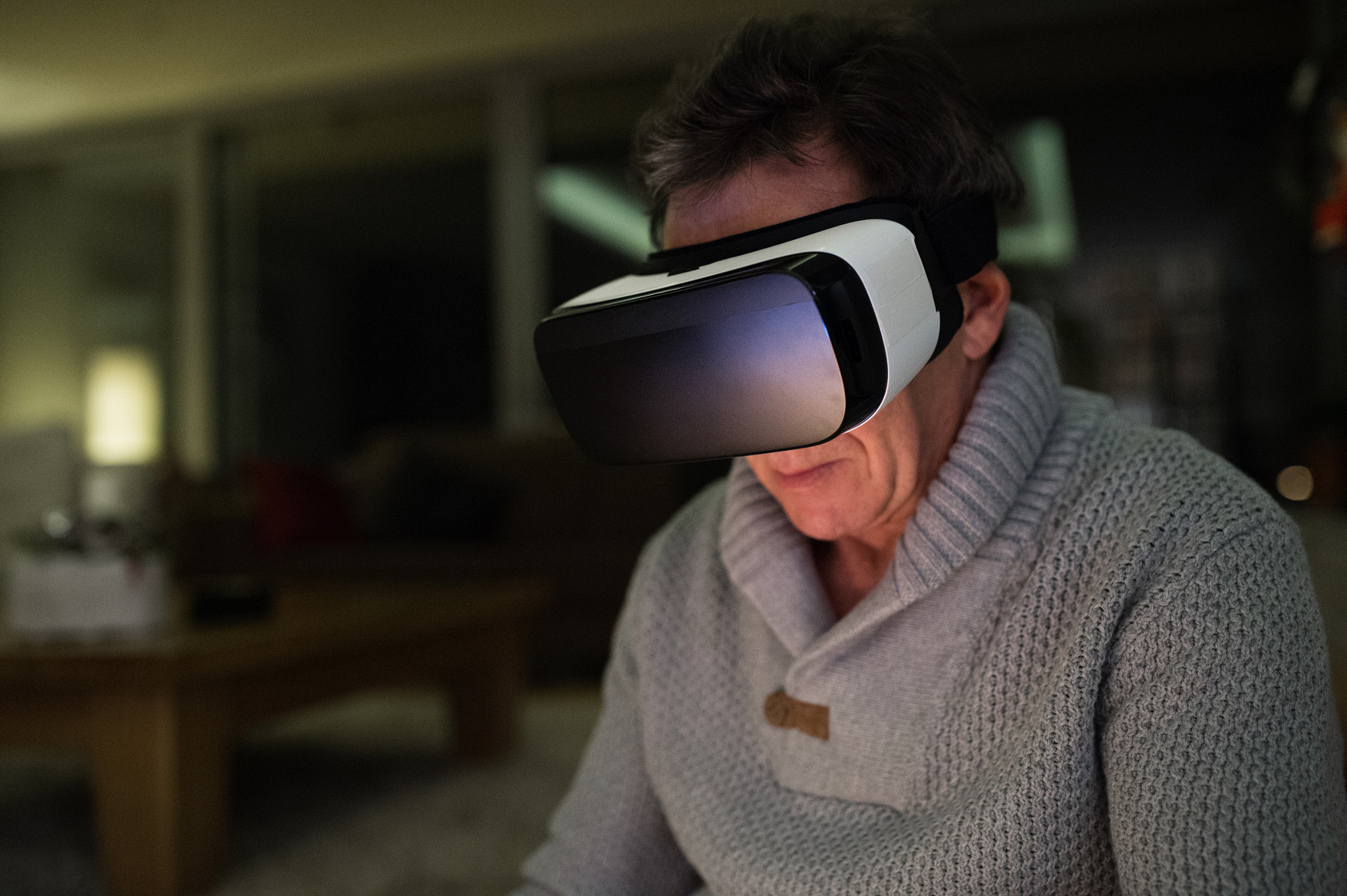 Senior man wearing virtual reality goggles at home