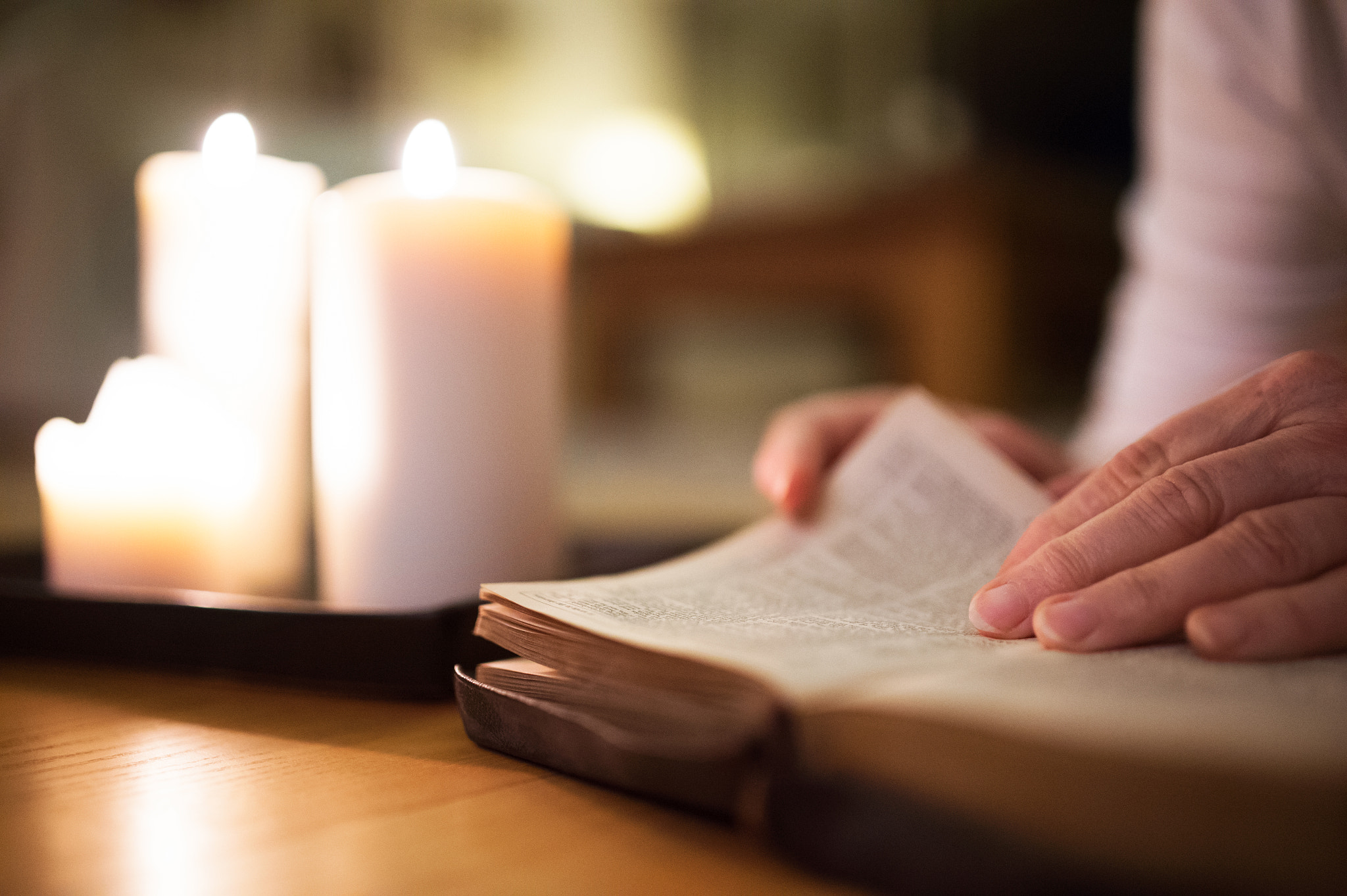 Nikon D4S + Sigma 35mm F1.4 DG HSM Art sample photo. Unrecognizable woman reading bible. burning candles next to her. photography