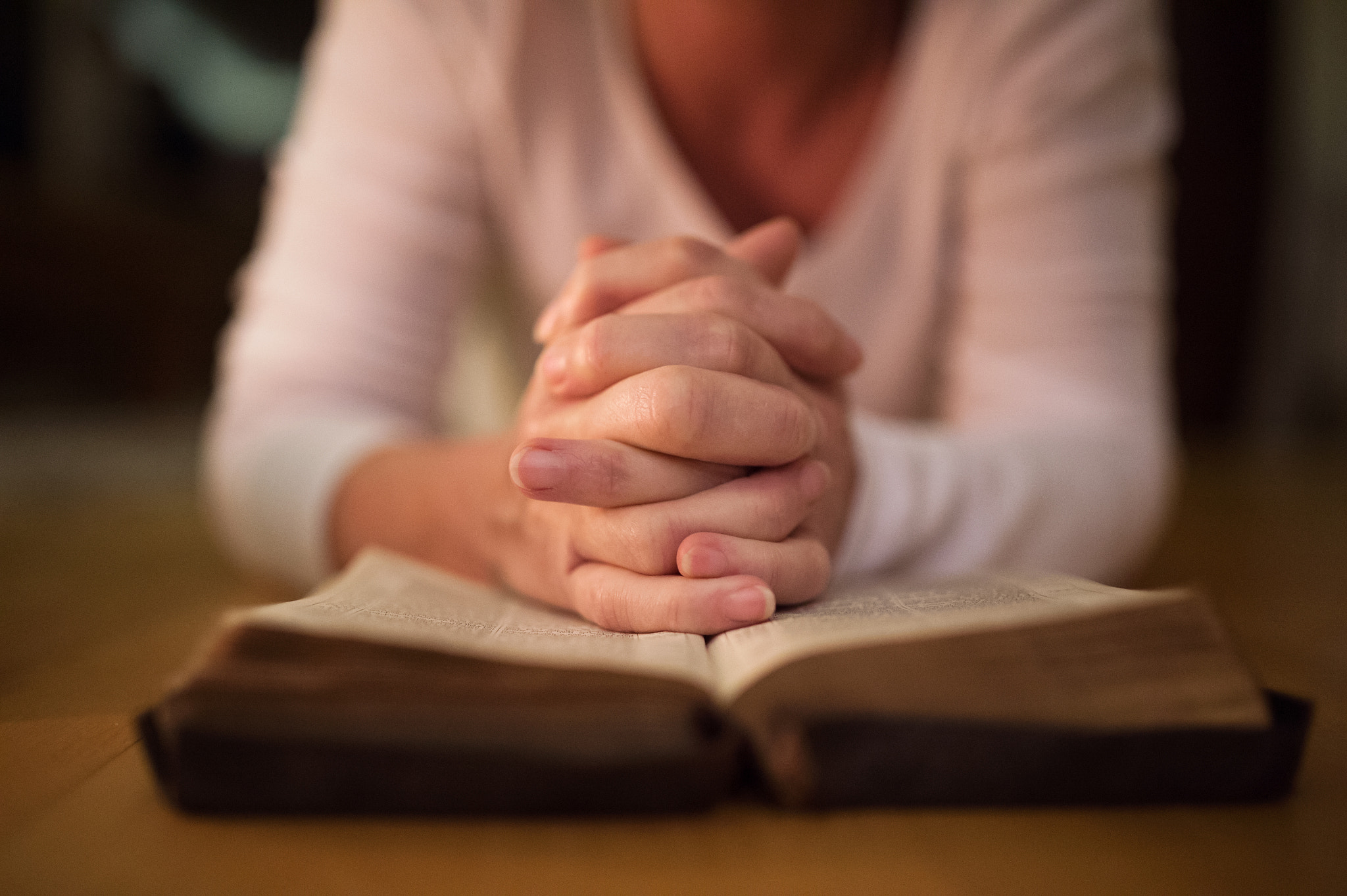 Nikon D4S sample photo. Unrecognizable woman praying, hands clasped together on her bibl photography