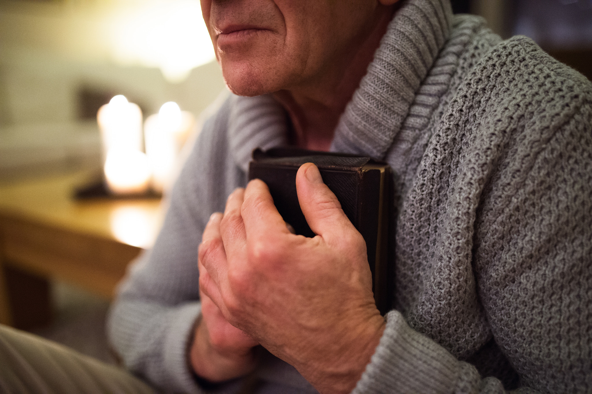 Nikon D4S + Sigma 35mm F1.4 DG HSM Art sample photo. Senior man praying, holding bible, burning candles behind him photography