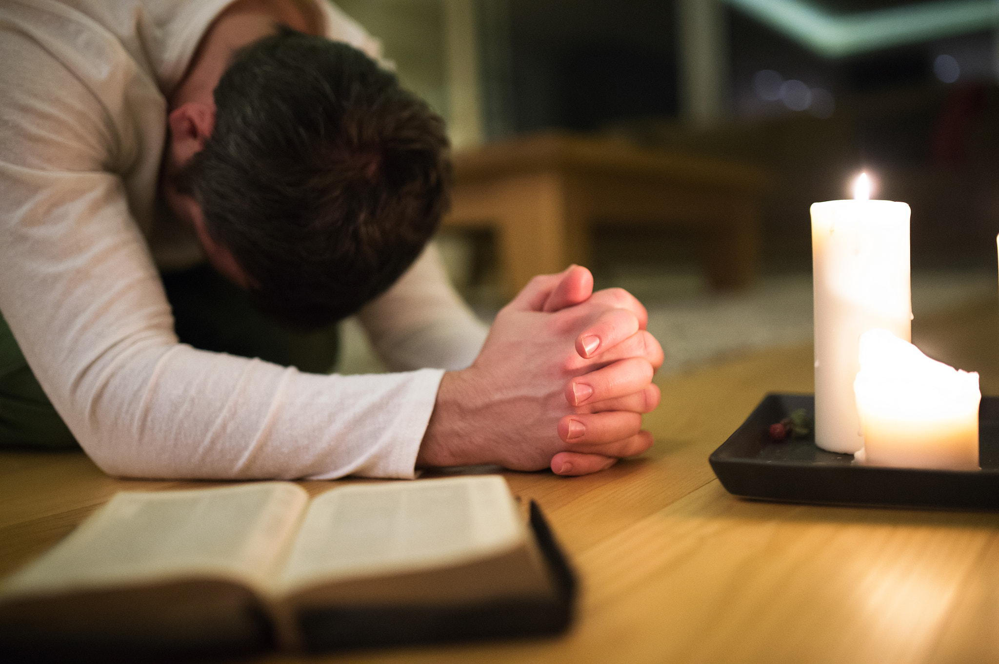 Nikon D4S sample photo. Young man praying, kneeling, bible and candle next to him. photography