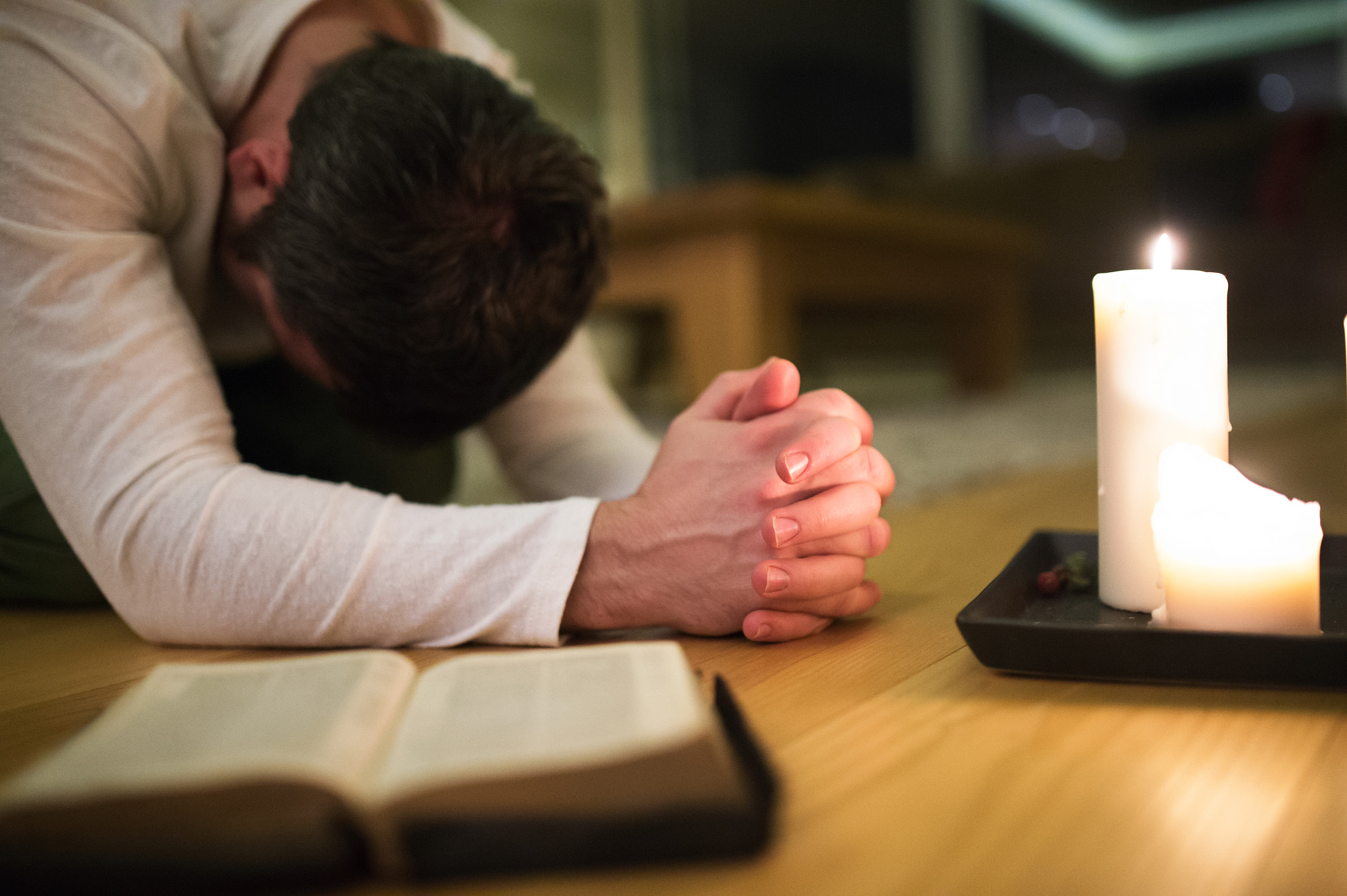 Nikon D4S + Sigma 35mm F1.4 DG HSM Art sample photo. Young man praying, kneeling, bible and candle next to him. photography