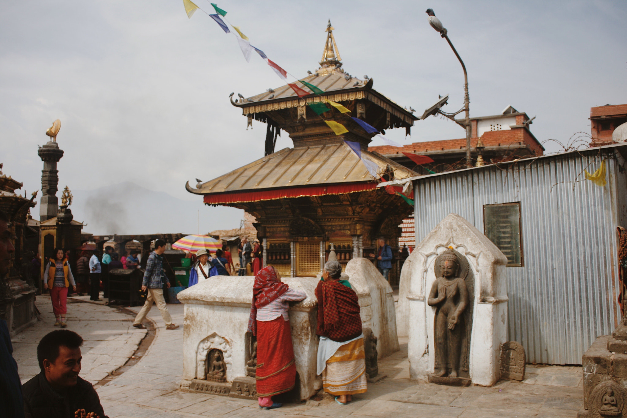 Canon EOS 400D (EOS Digital Rebel XTi / EOS Kiss Digital X) sample photo. Elderly lady in front of ancient newari temple photography