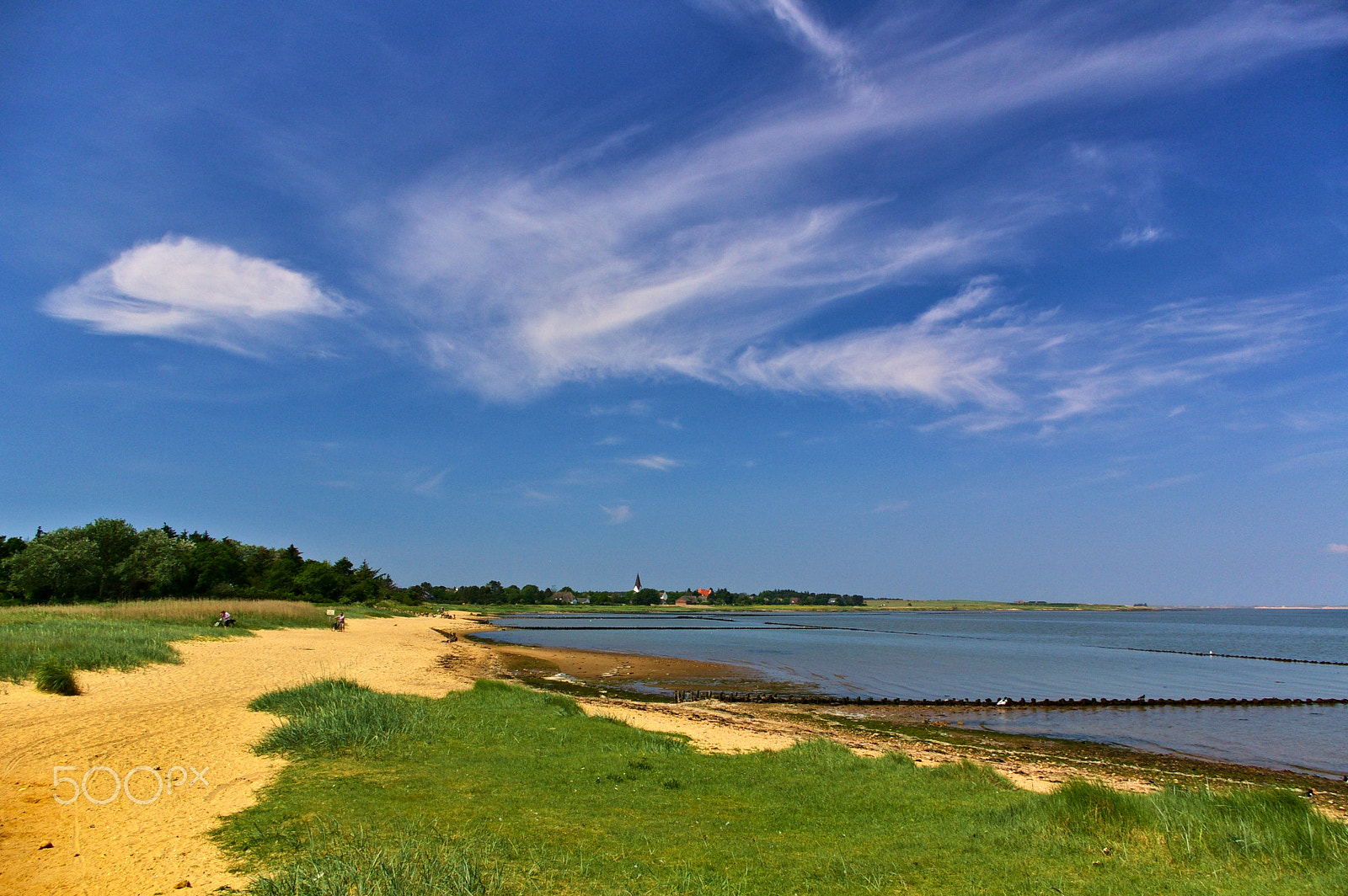 Pentax K100D sample photo. Sandy beach with grass, tidal mudflats and village with church spire across the bay photography