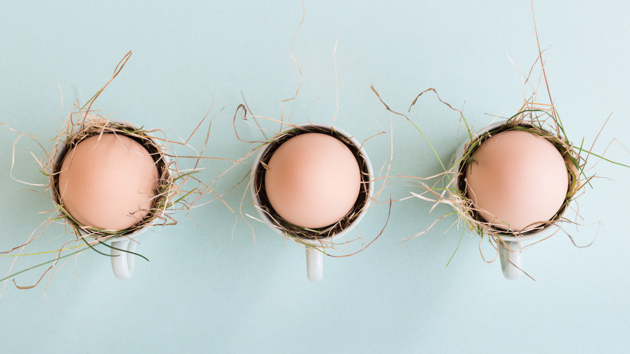 Uncolored natural easter eggs in espresso cups; happy easter concept; green minimalist easter...