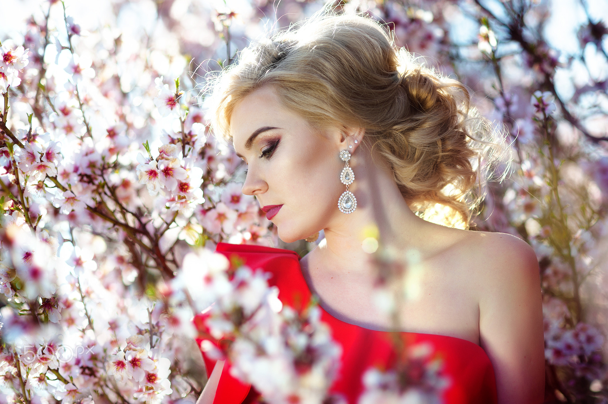 Happy young blonde woman in spring flowers garden lifestyle portrait.