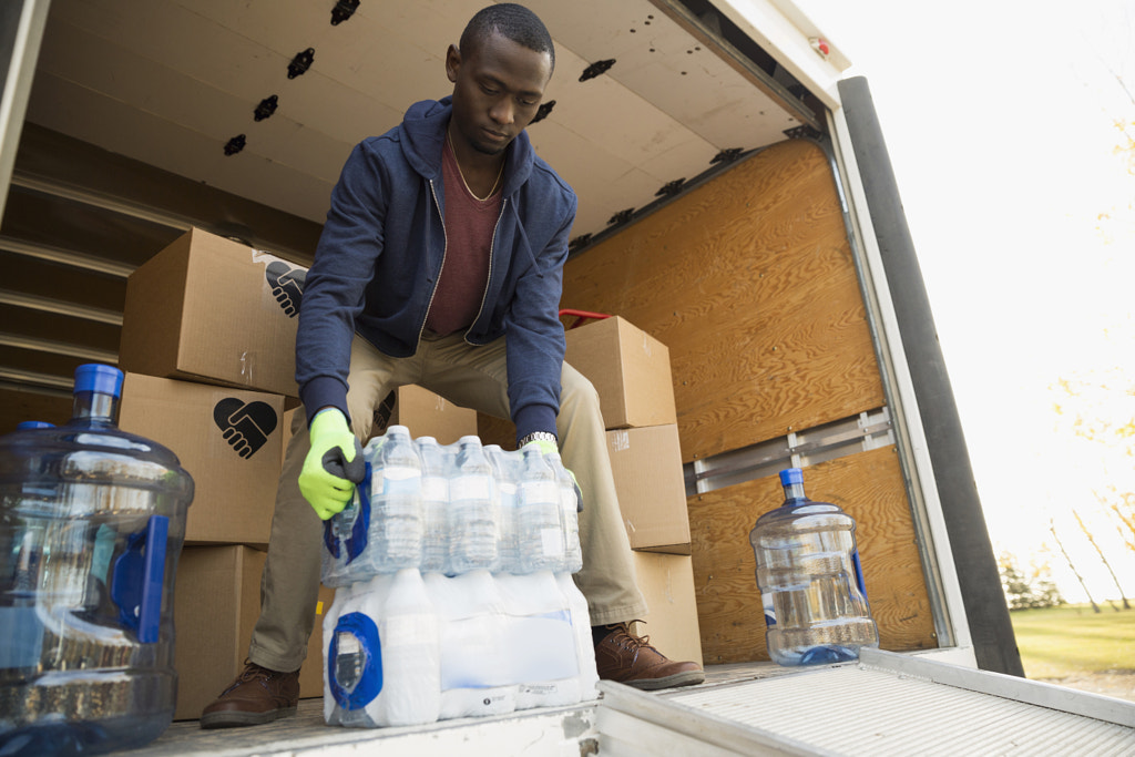 Volunteer unloading water bottle cases on truck by Hero Images Hero Images on 500px.com