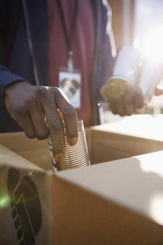 Volunteer packing tin cans into cardboard box by Hero Images Hero Images on 500px.com