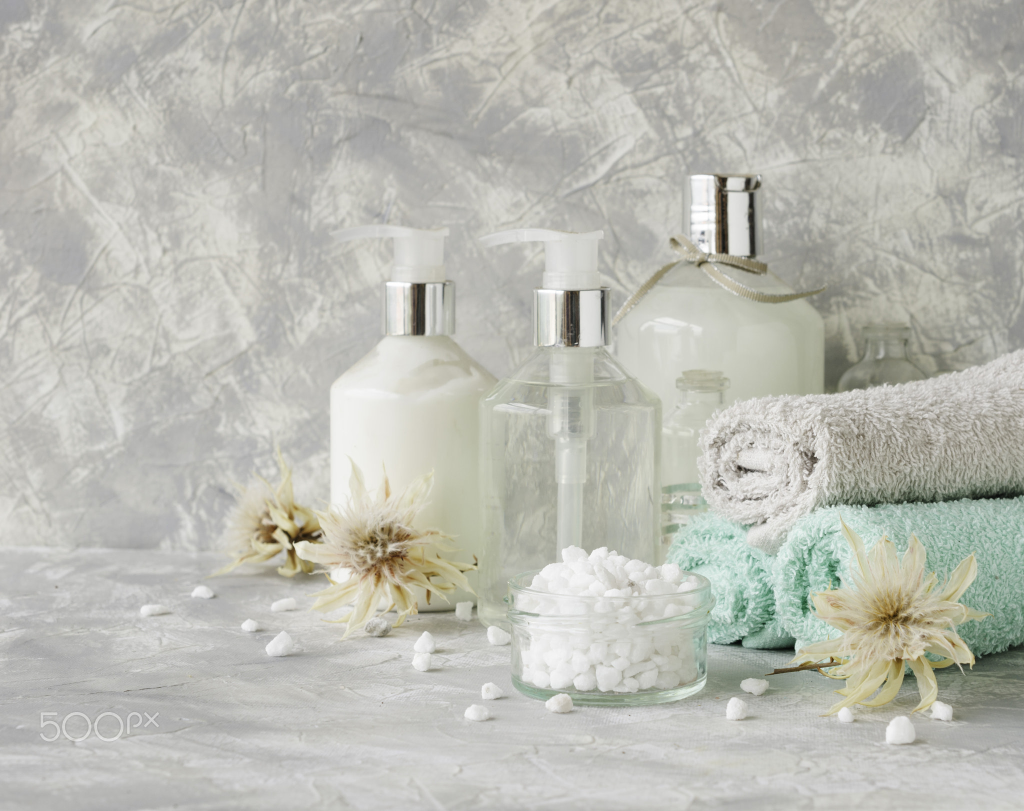 Spa set on a white marble table with a stack of towels, selective focus