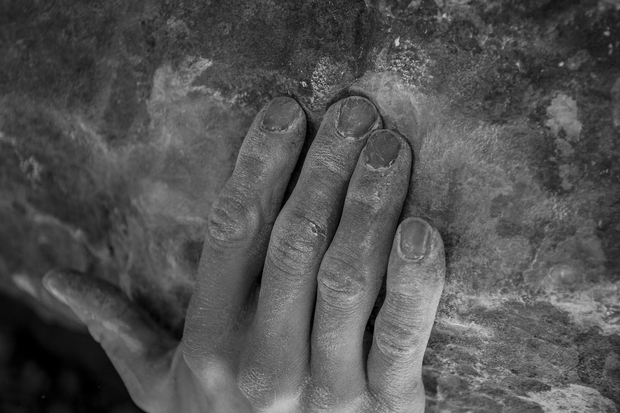 Close up black and white shot of male hand in chalk holding rock