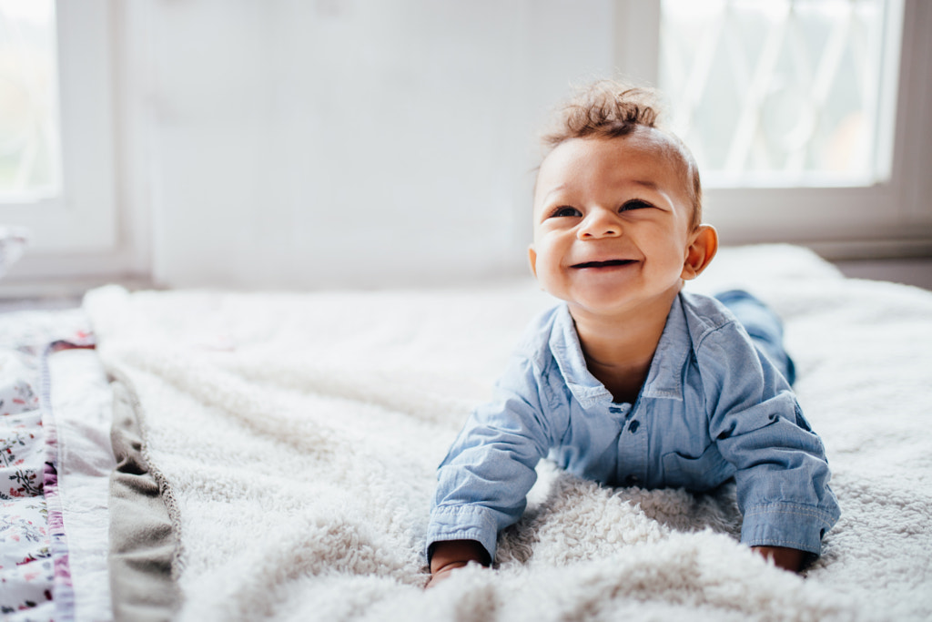 Cute adorable toddler smiling while laying on bed by Carina König on 500px.com