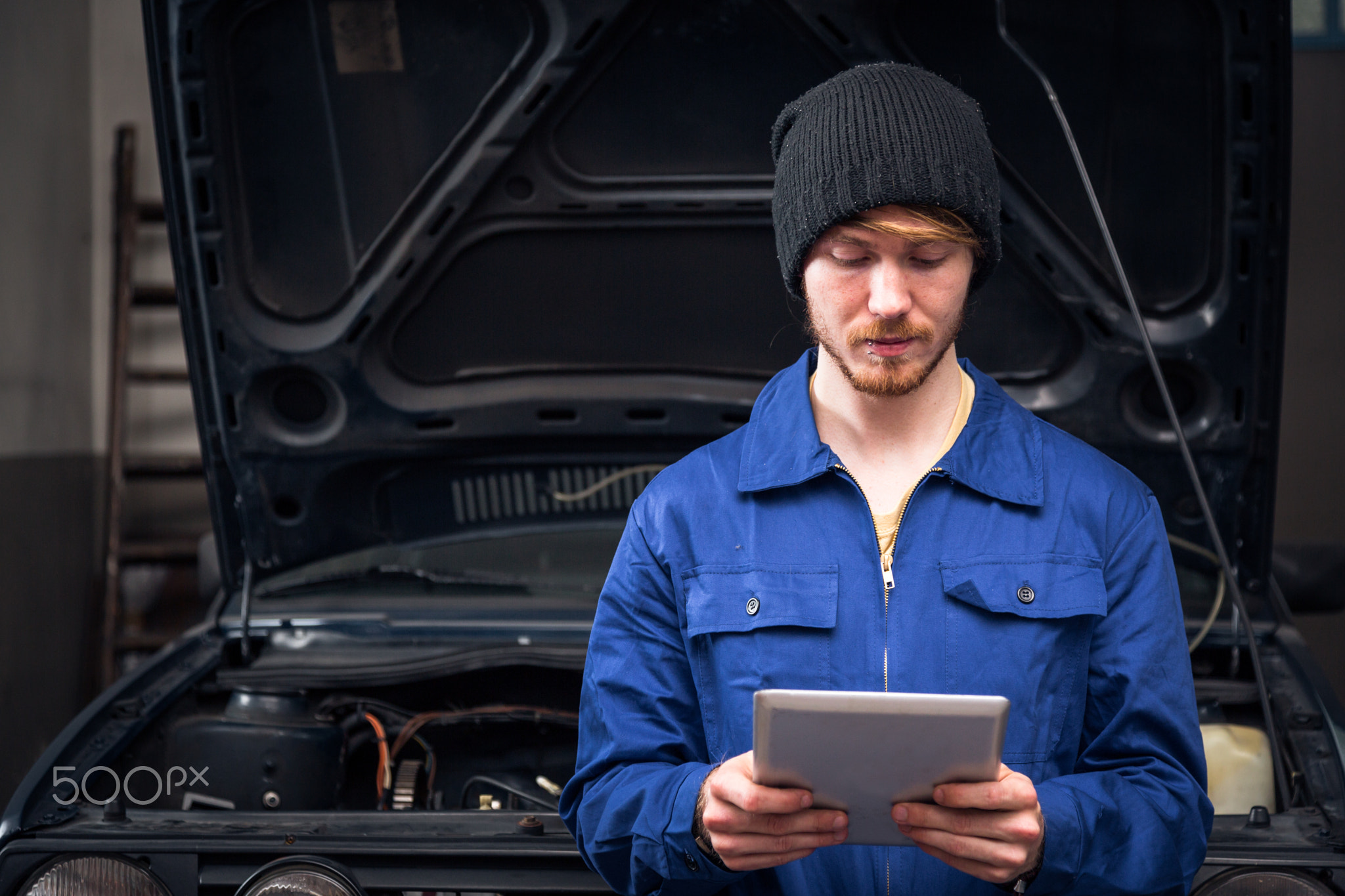 Mechanic Checking A Car Engine Using Digital Tablet