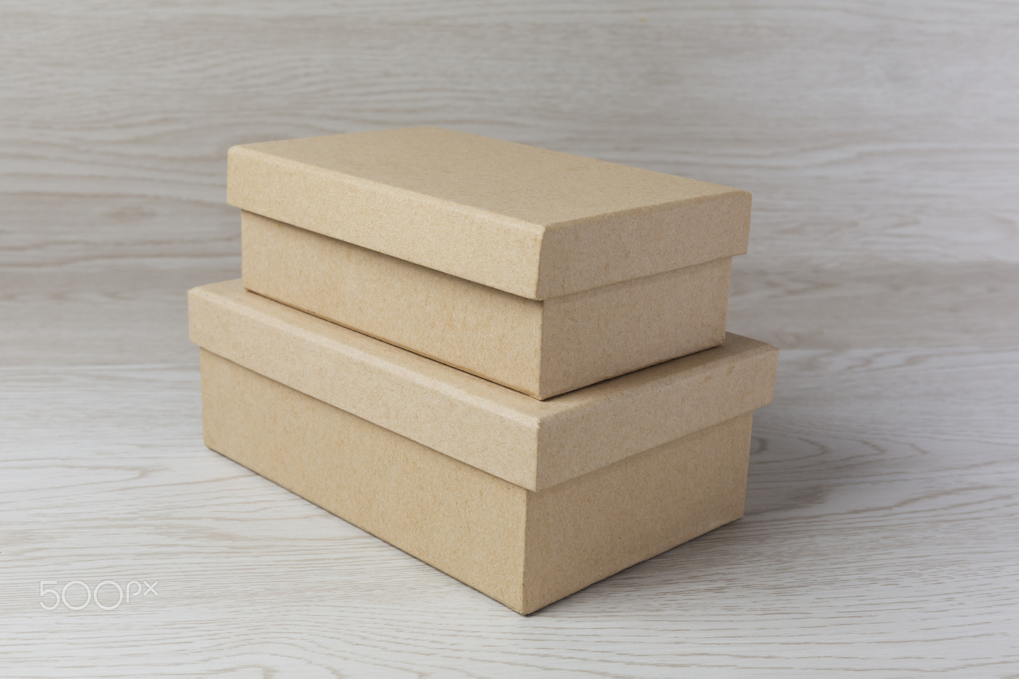Two small raw plain boxes for small items on white wooden background. With shadow.