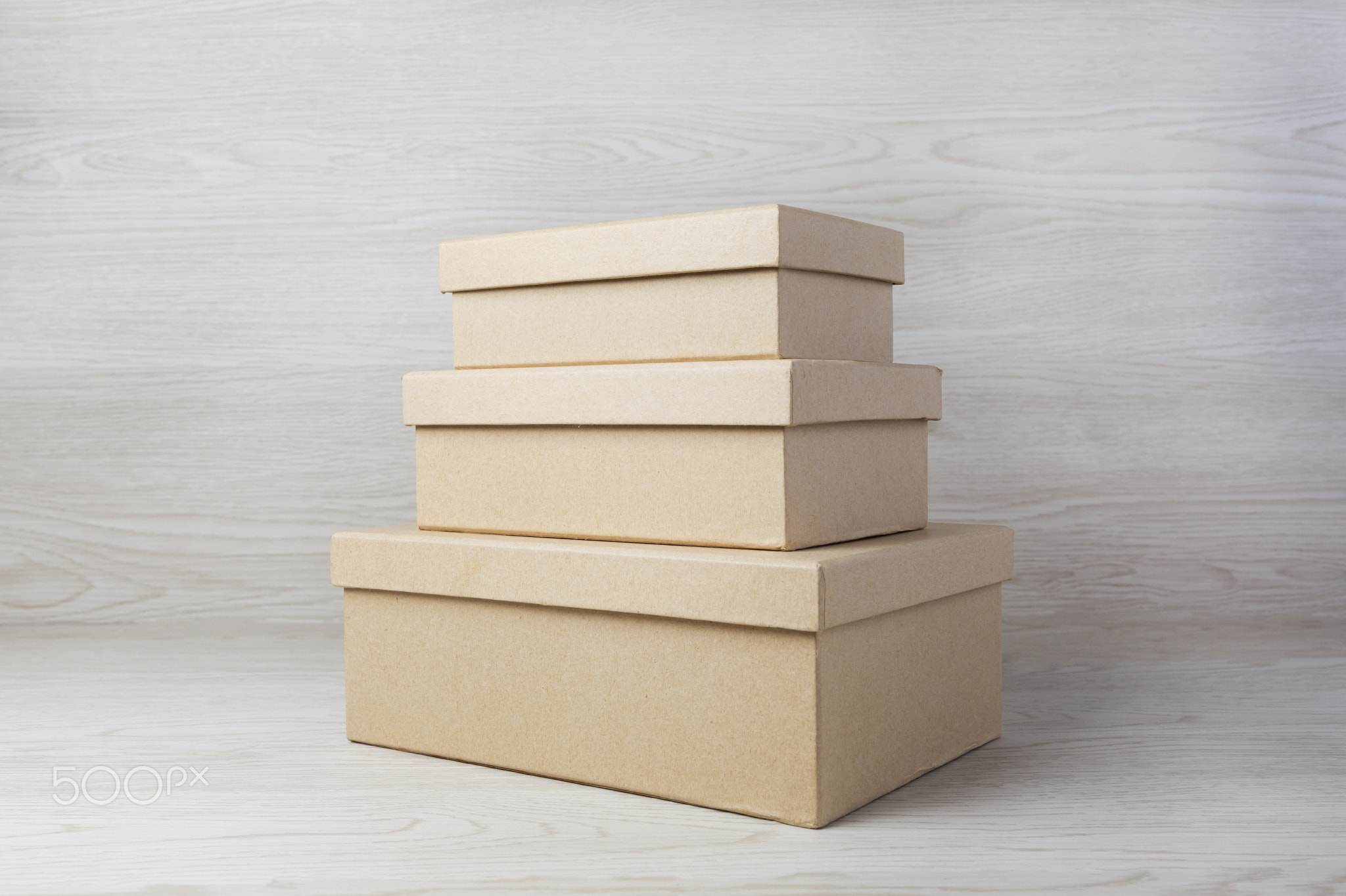 Three small raw plain boxes for small items on white wooden background. With shadow.