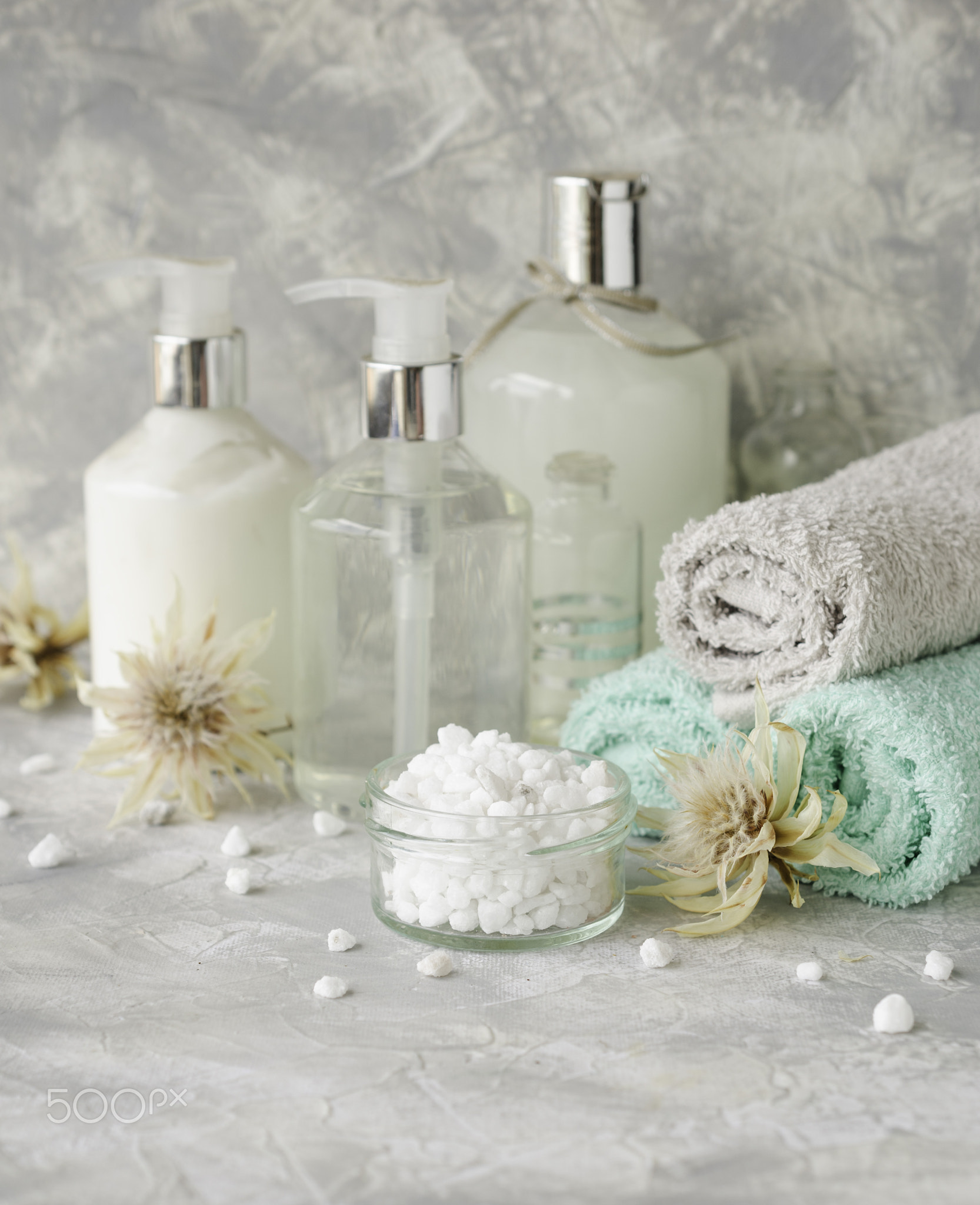 Spa set on a white marble table with a stack of towels, selective focus