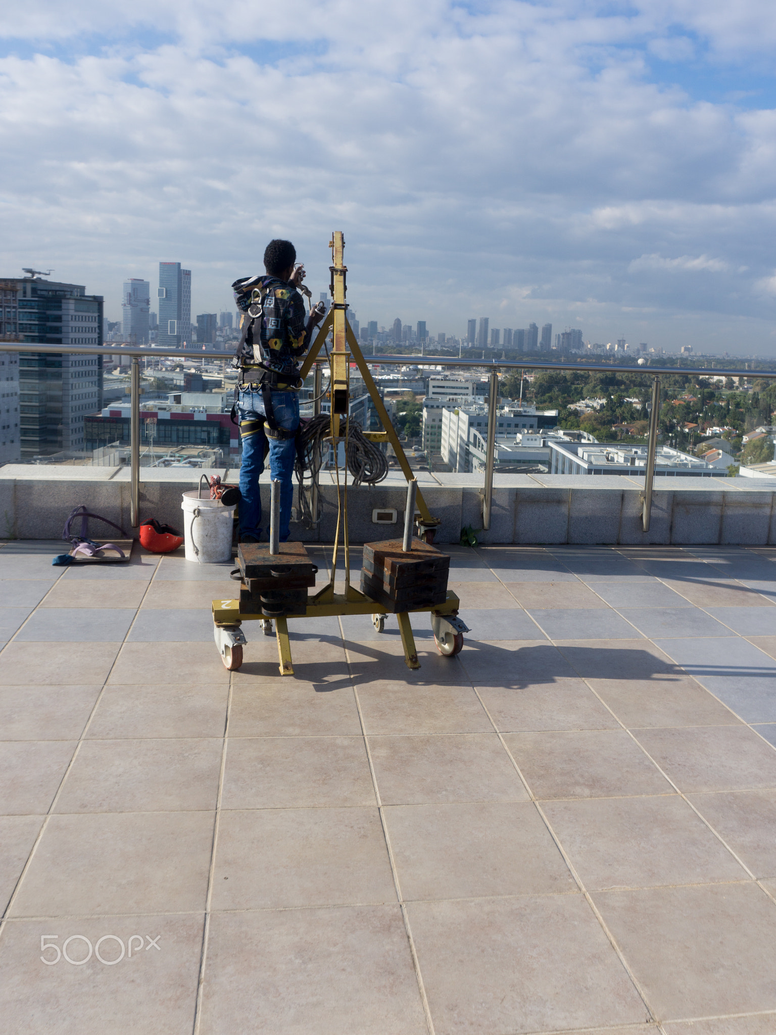 Window cleaning employee with work tools and city background.