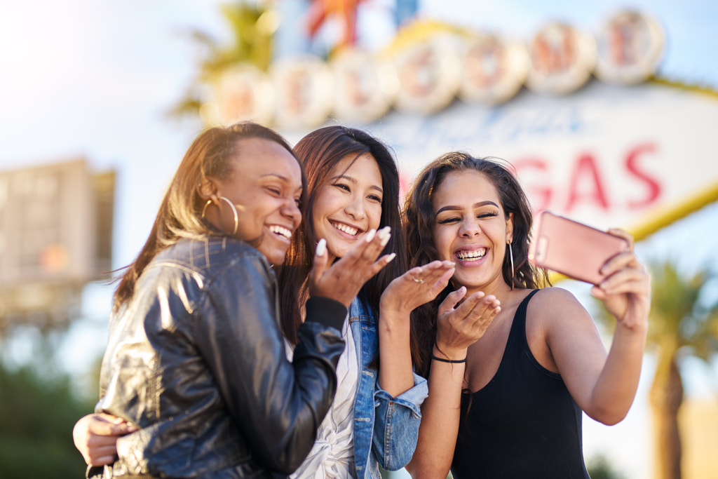 all girl group of friends having fun taking selfies in front of welcome to las vegas sign by Joshua Resnick on 500px.com