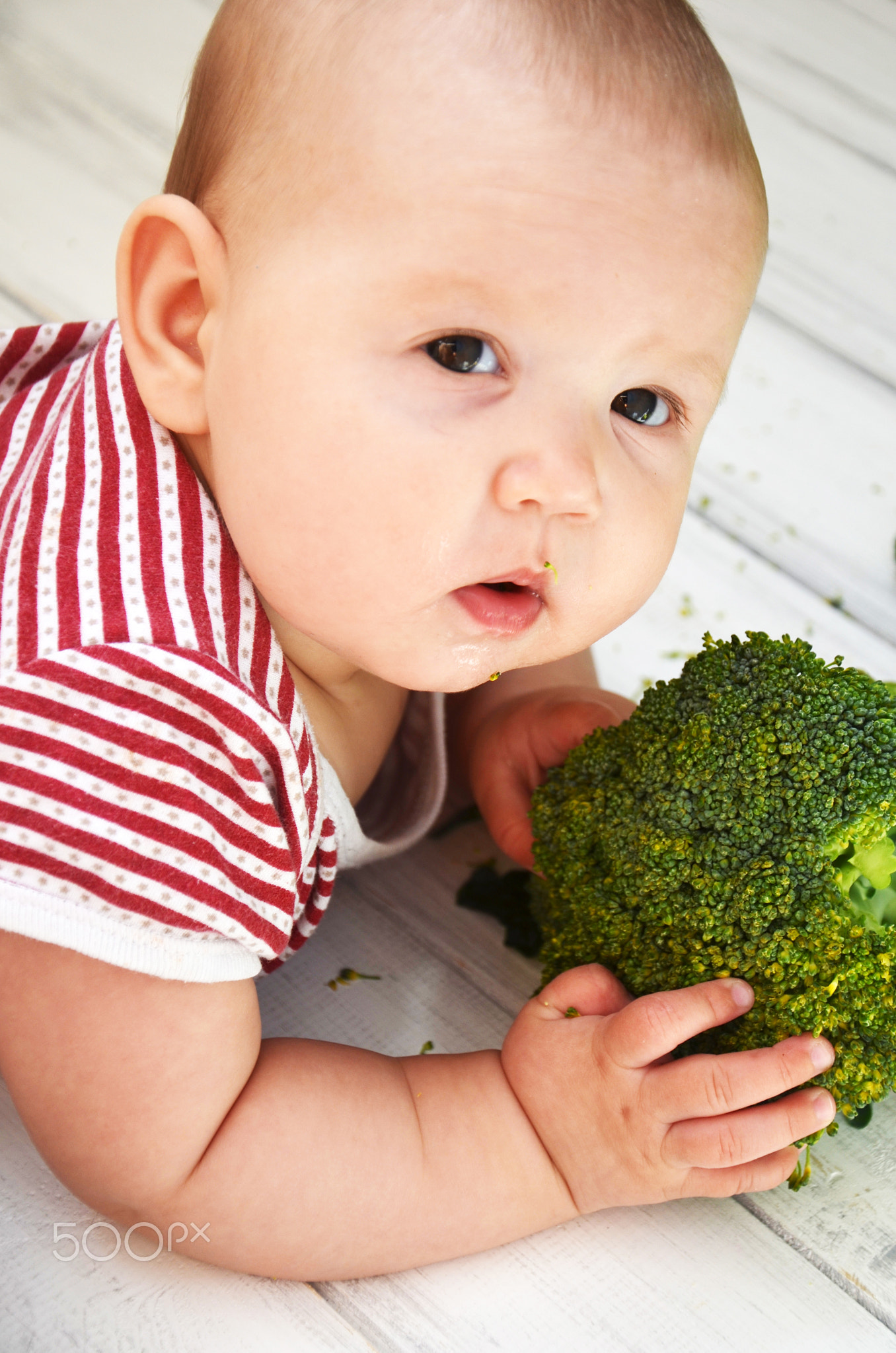 Child little girl eats vegetable. Little baby with broccoli. Baby with vegetables