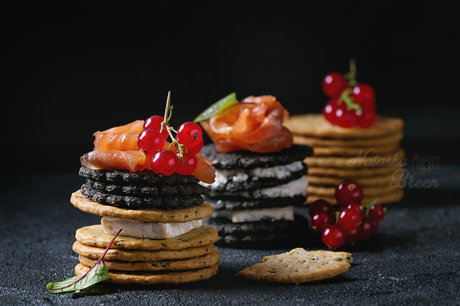 Black crackers with salmon and berries