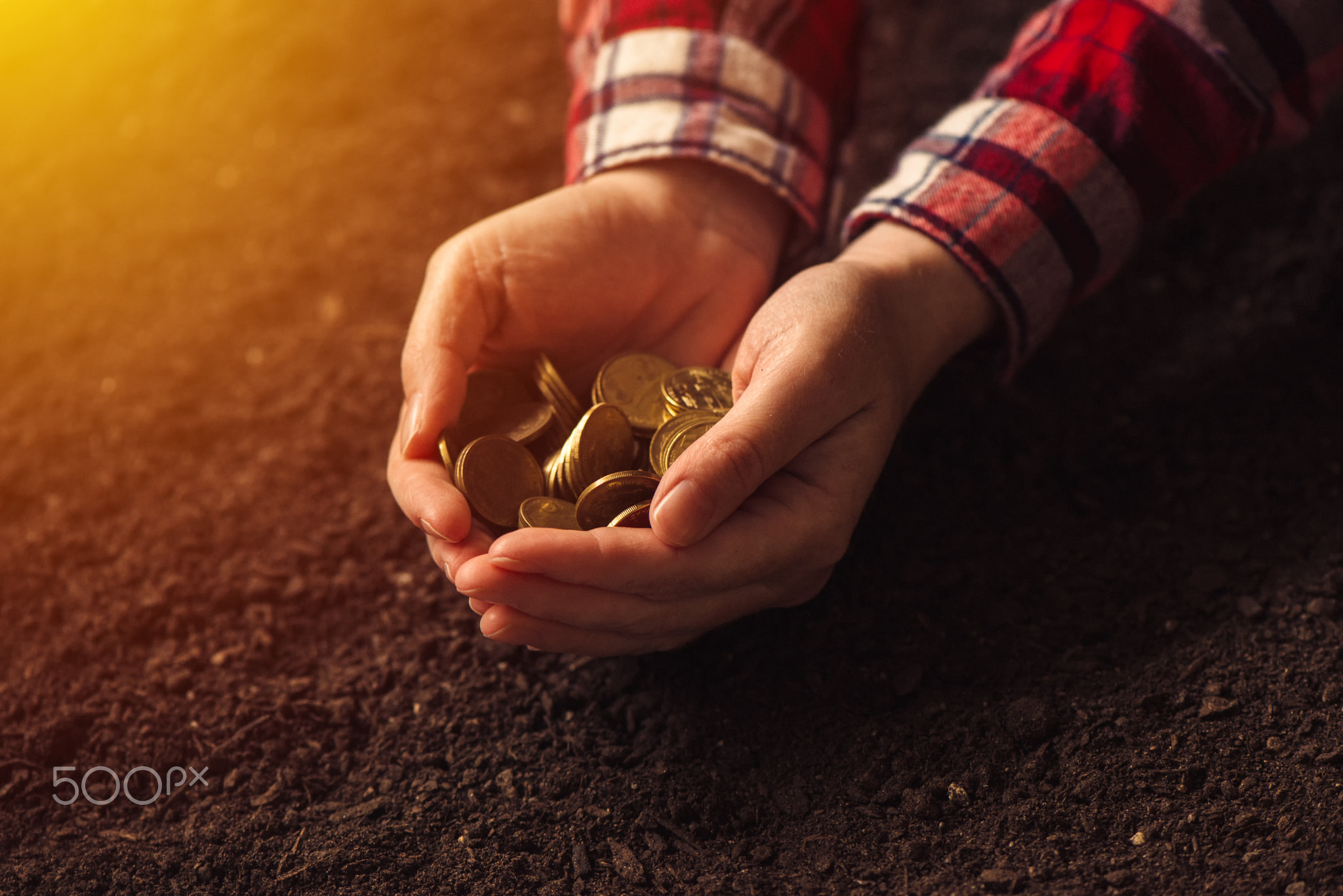 Farmer with handful of coins over soil land