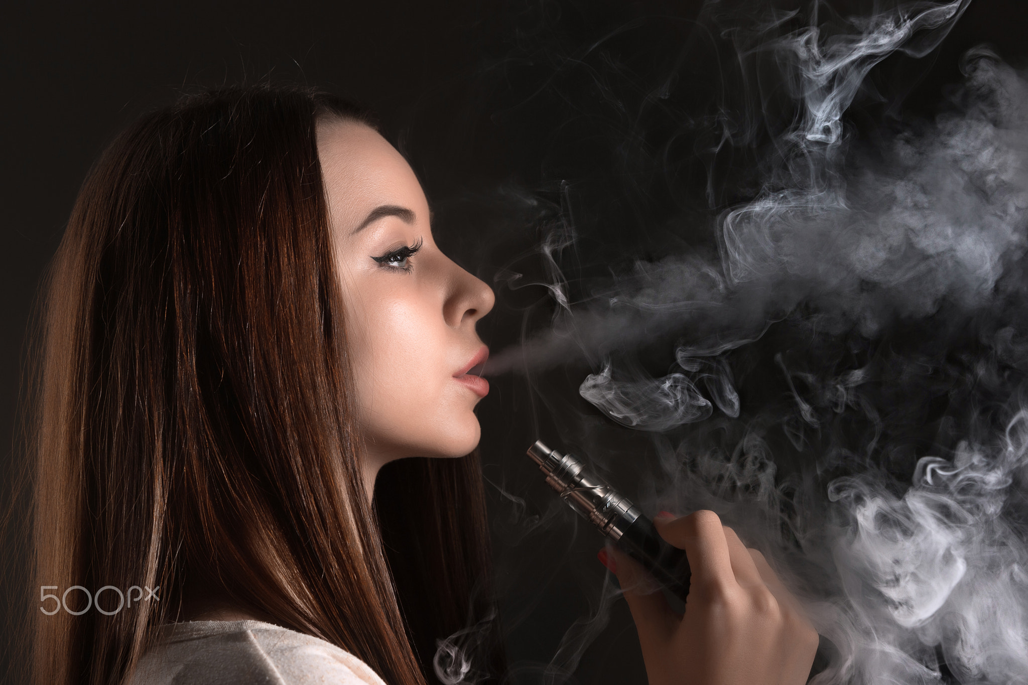 The face of vaping young woman at black studio