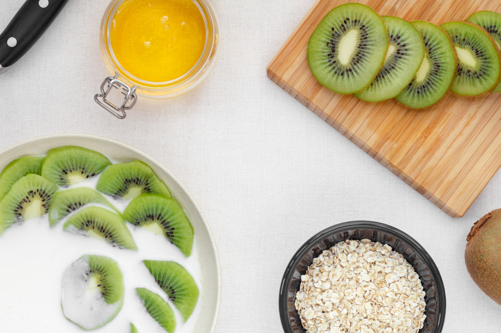 Top view on health breakfast with fresh sliced kiwi, milk, oatmeal and honey. by Edalin Photography on 500px.com