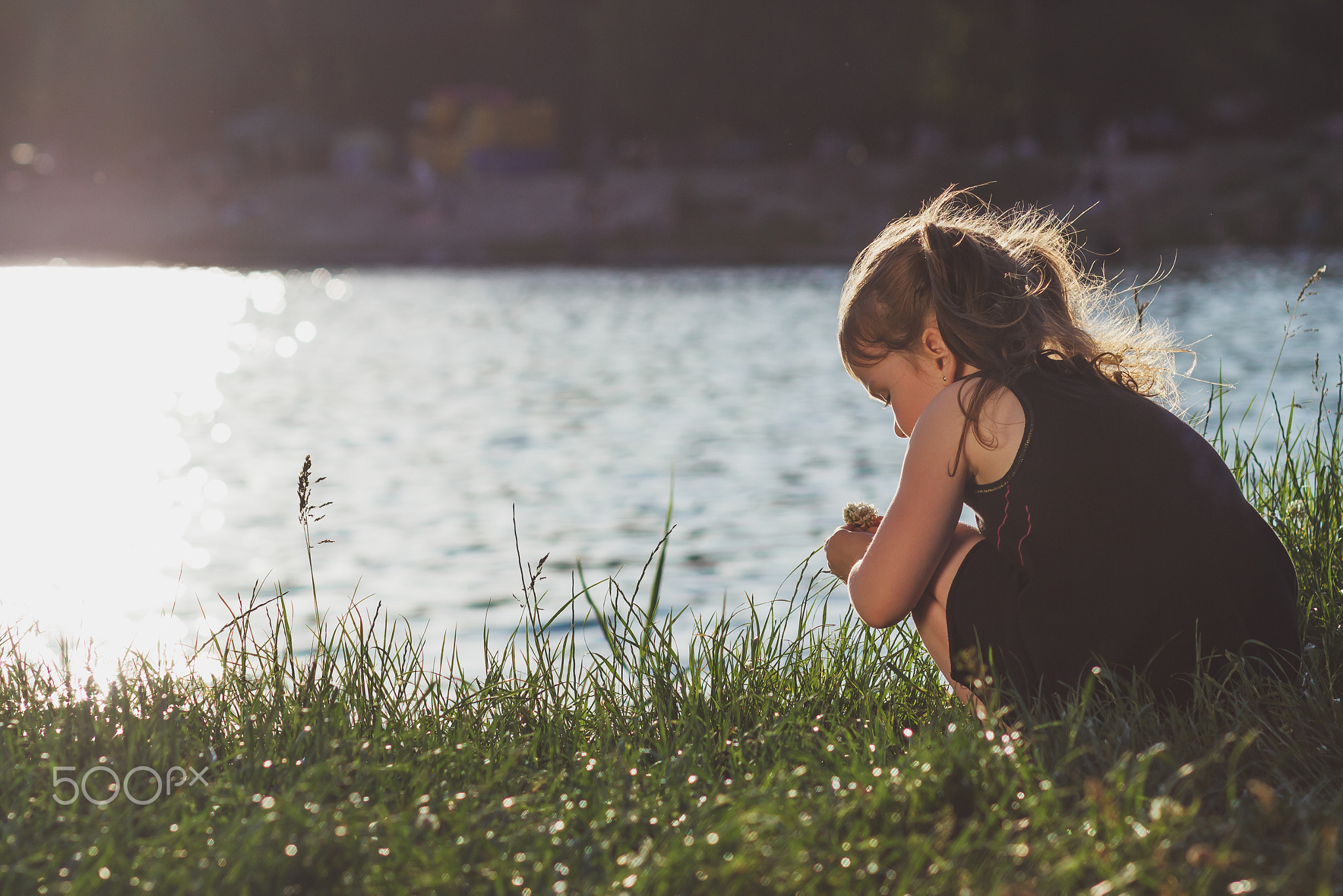 Little girl is playing on the river bank in summer