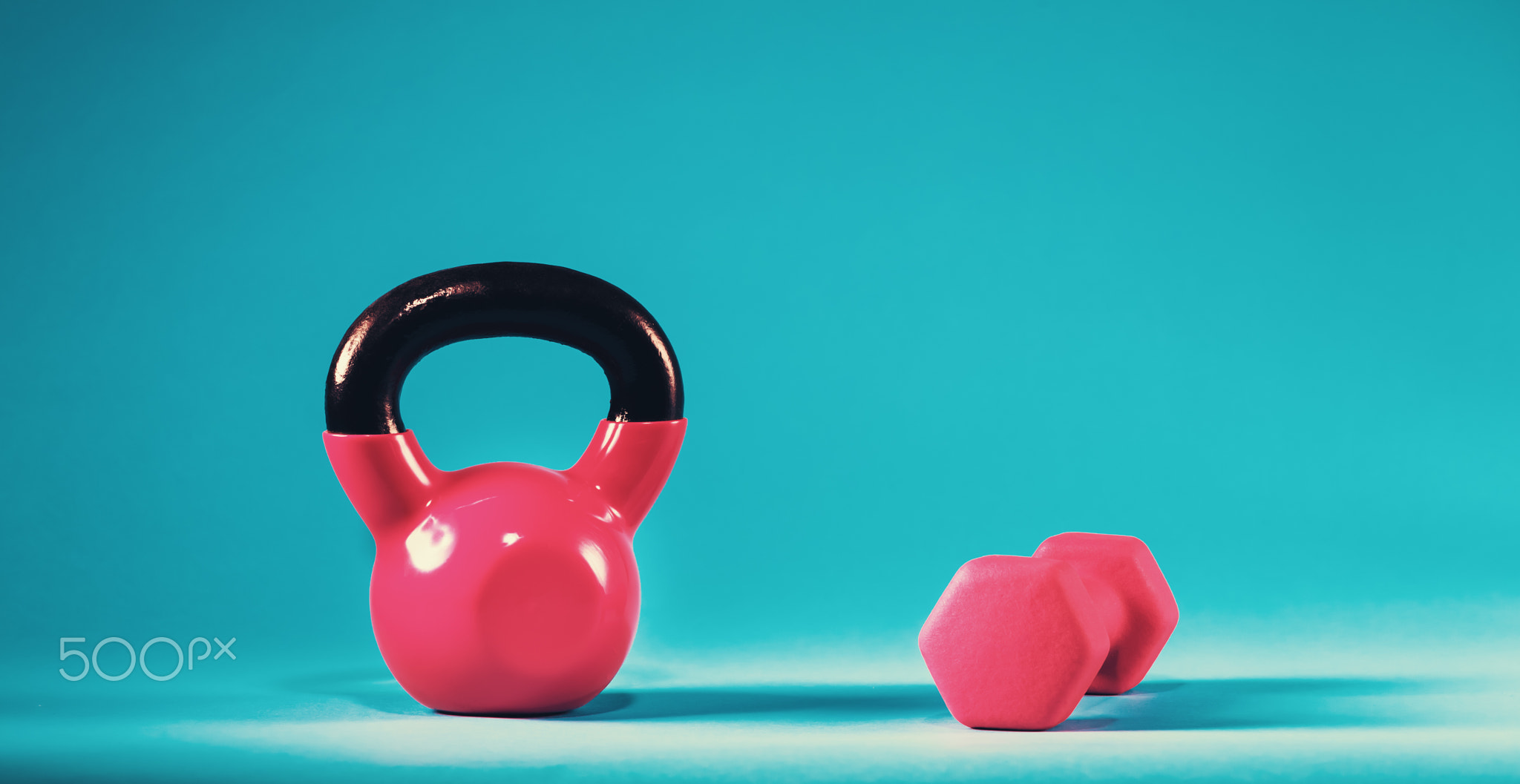 Pink kettlebell and dumbbell on a blue background