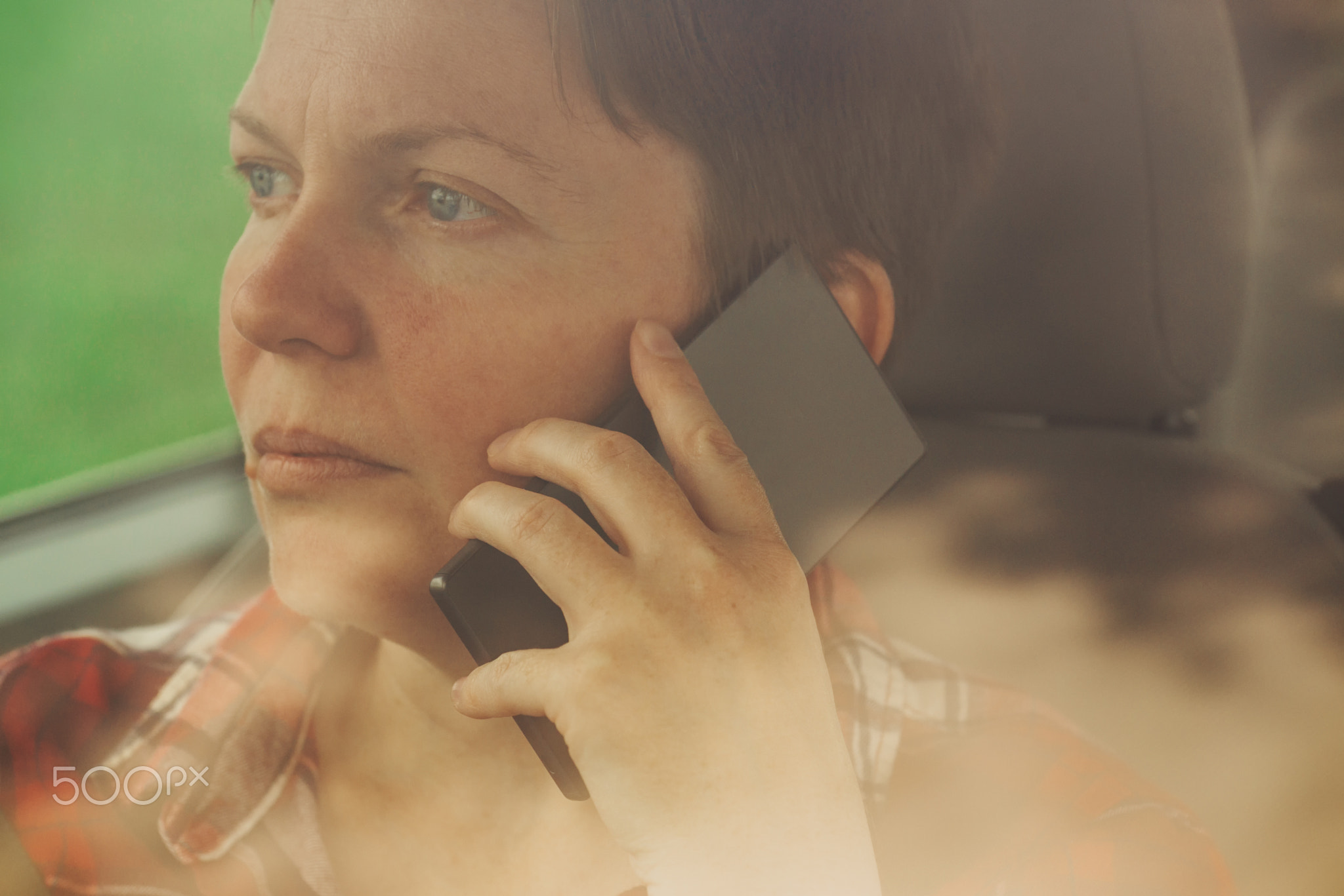 Worried woman talking on mobile phone in car